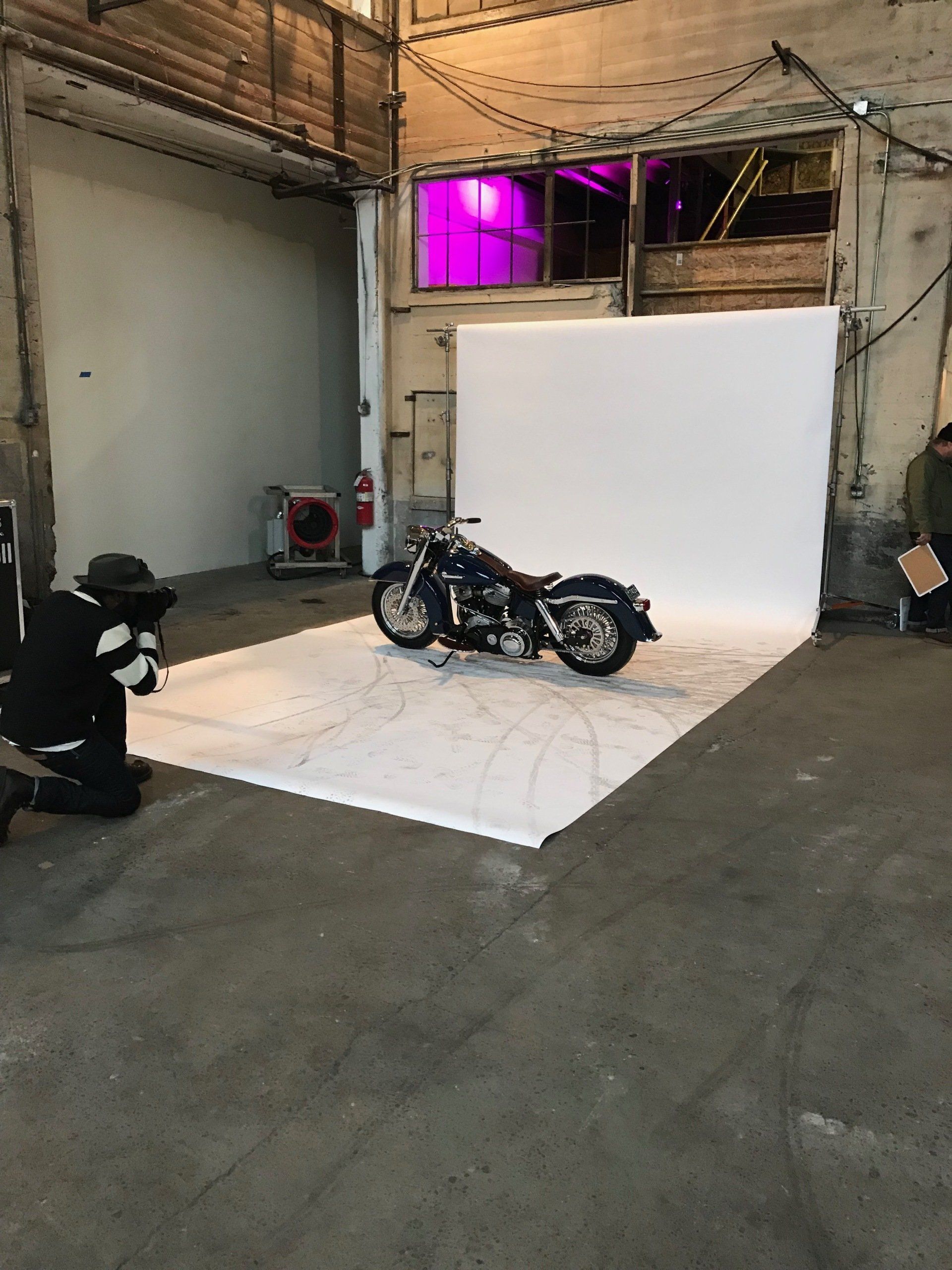 A motorcycle is sitting on a white mat in a room