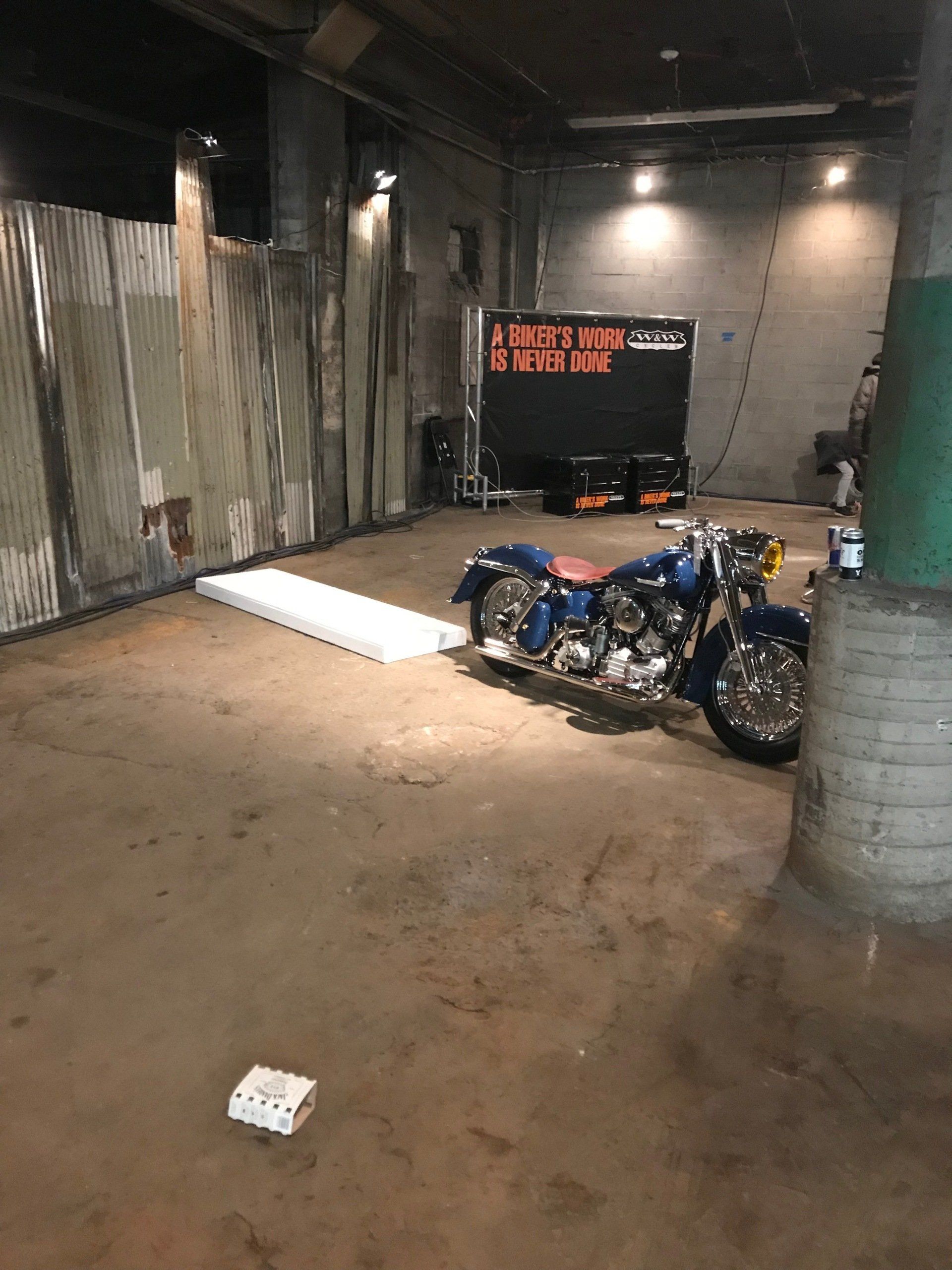 A blue motorcycle is parked in a garage next to a trailer.