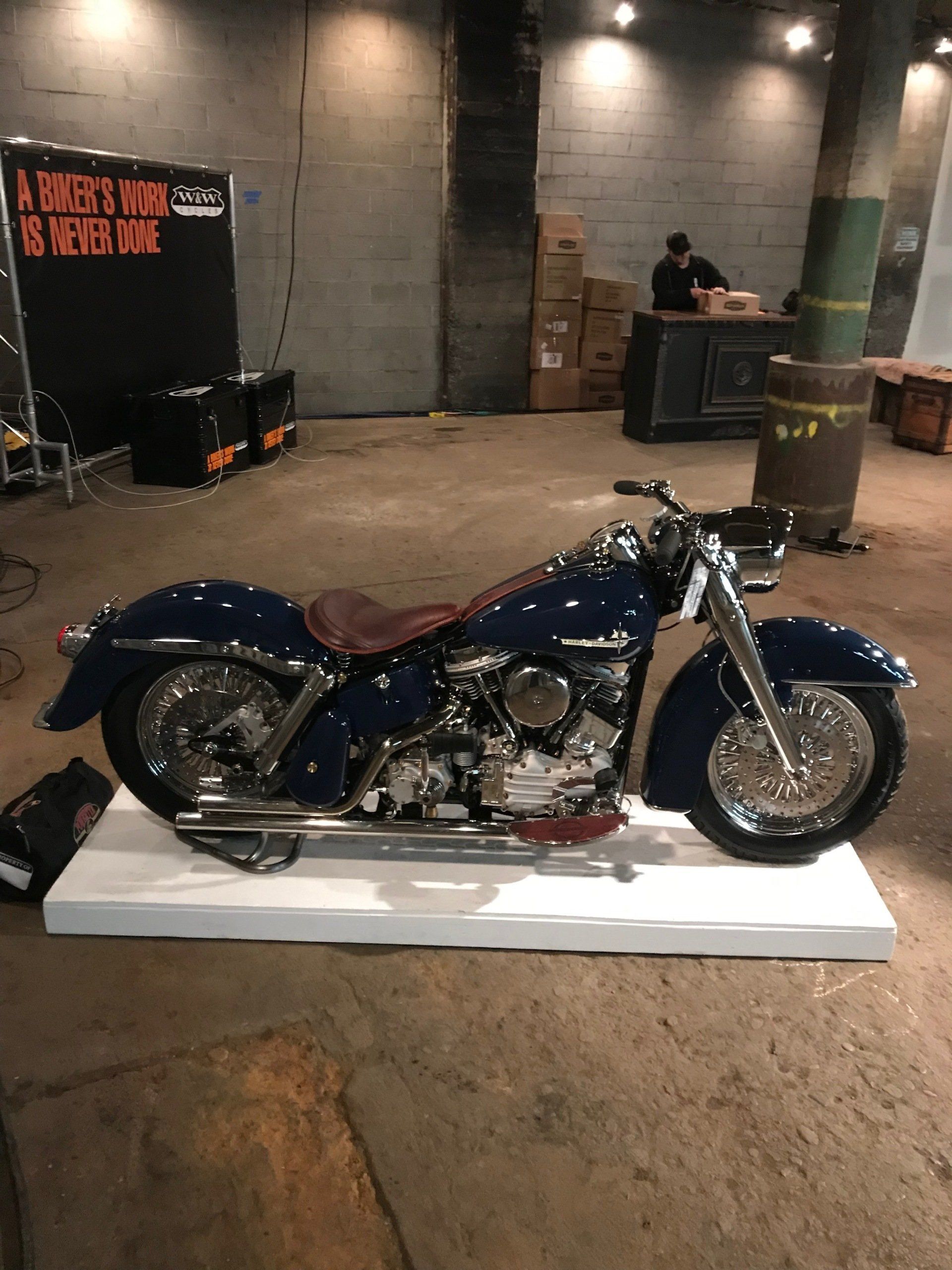 A blue motorcycle is on display in a warehouse.