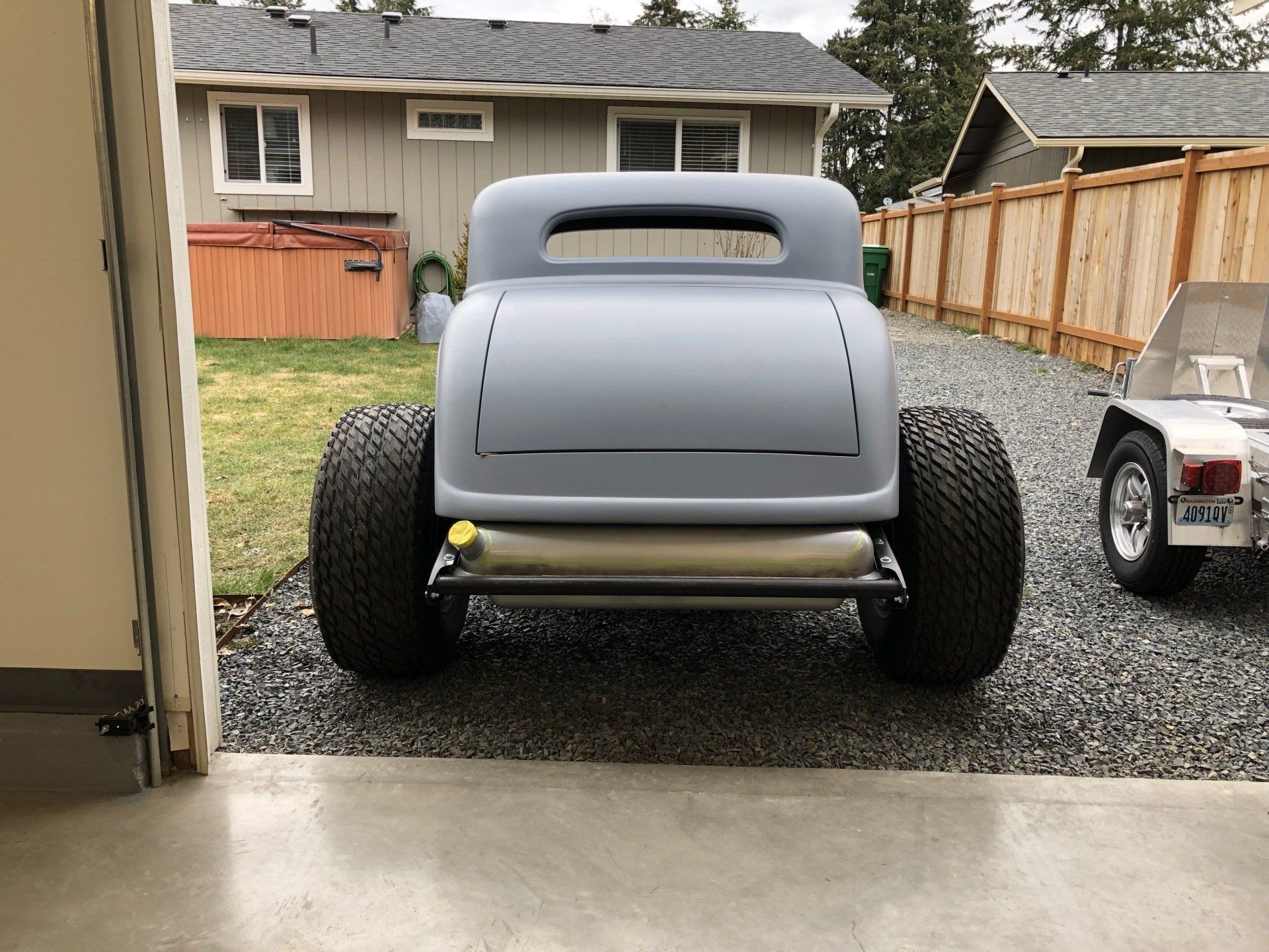 A hot rod is parked in a garage next to a golf cart.