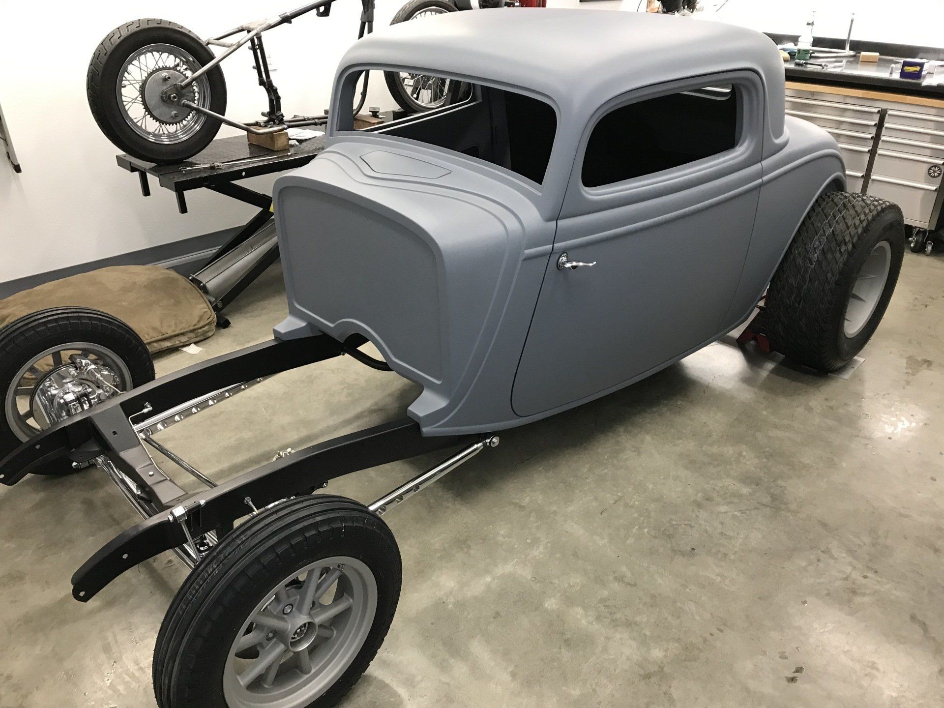 A gray car is sitting on a trailer in a garage.