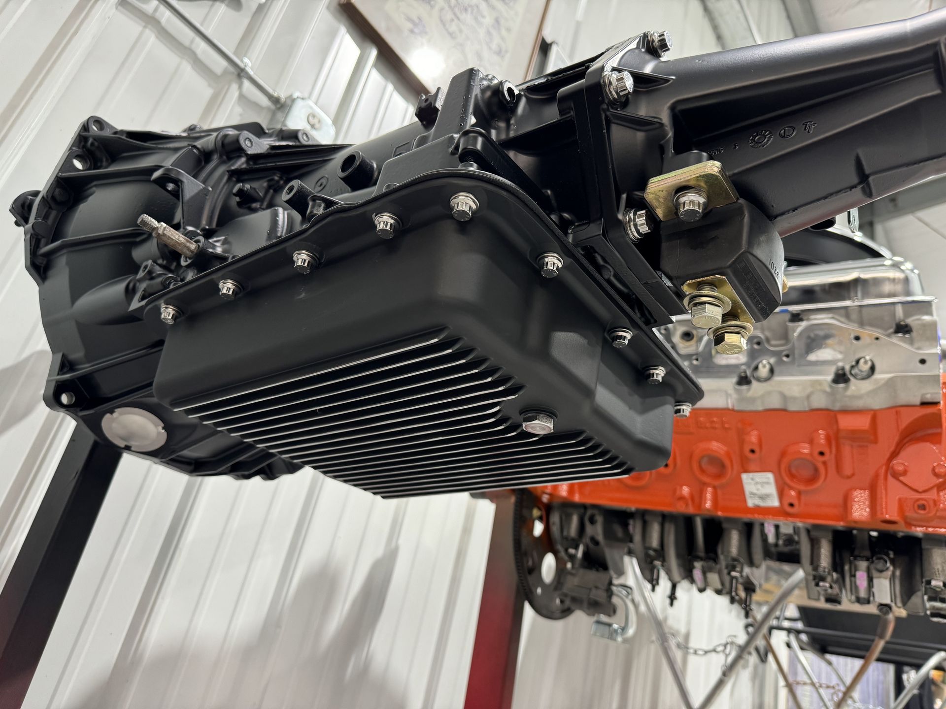 A close up of a car engine and transmission in a garage.