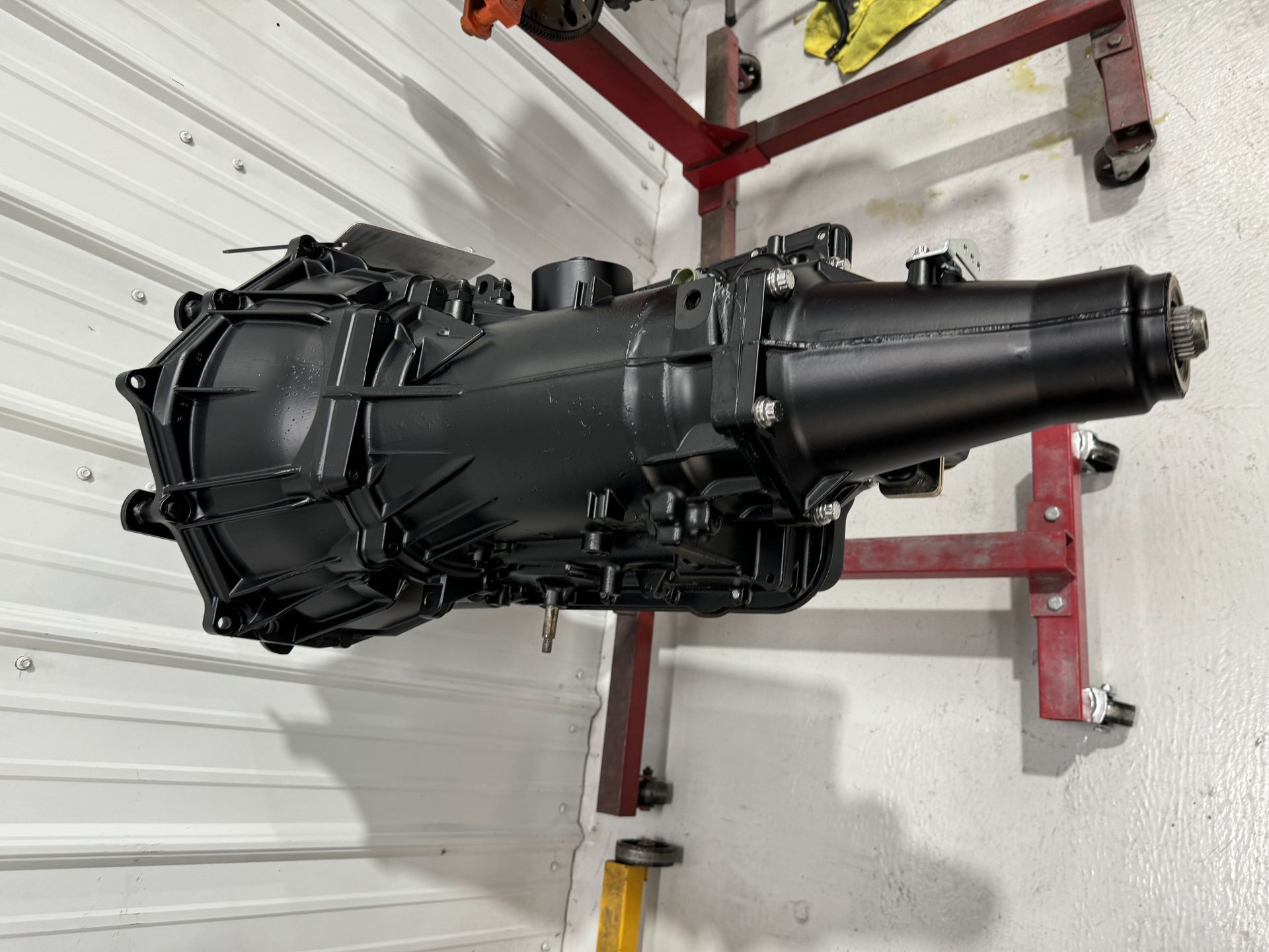 A black gearbox is sitting on top of a red stand.