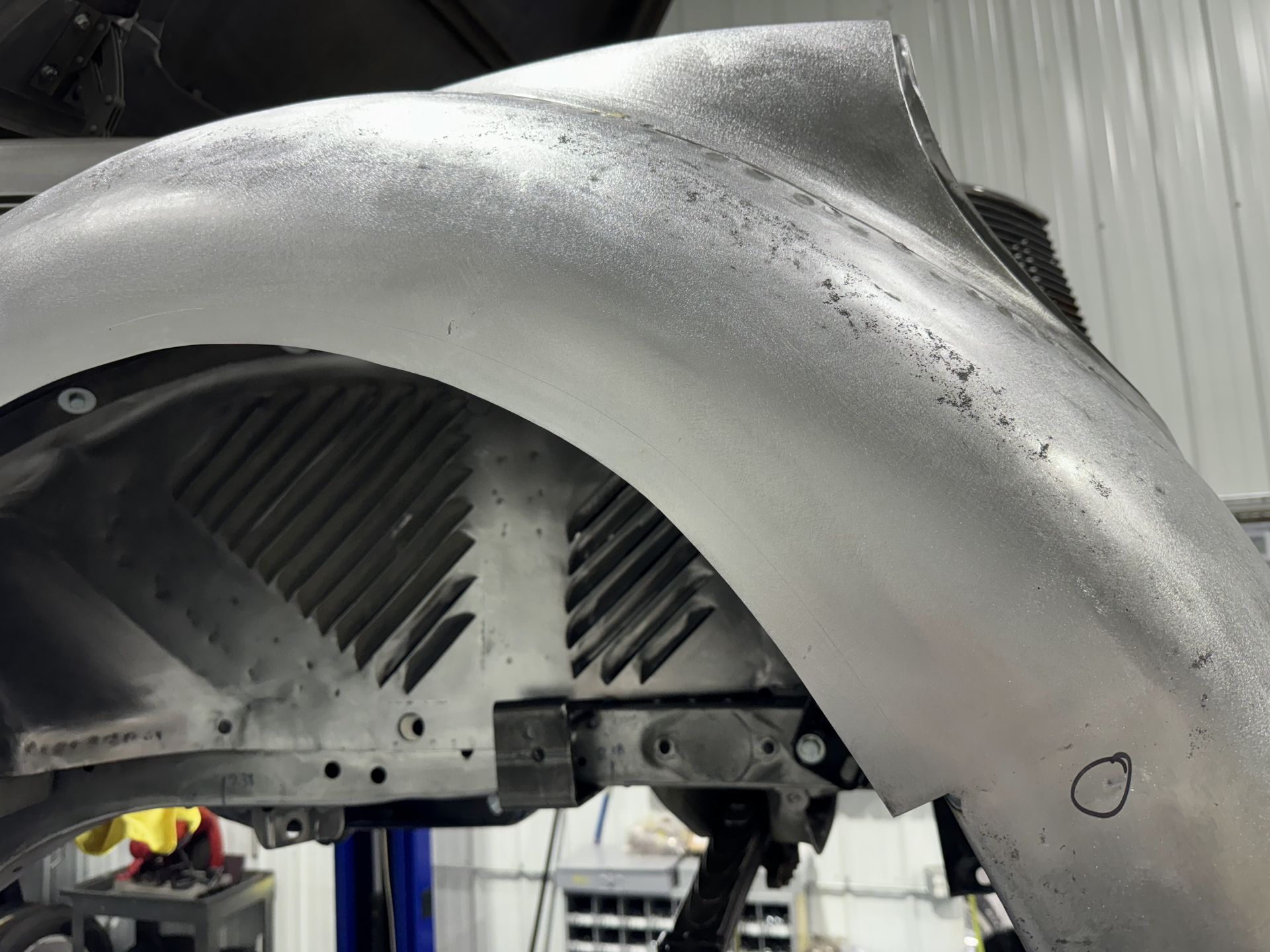 A close up of a car fender on a lift in a garage