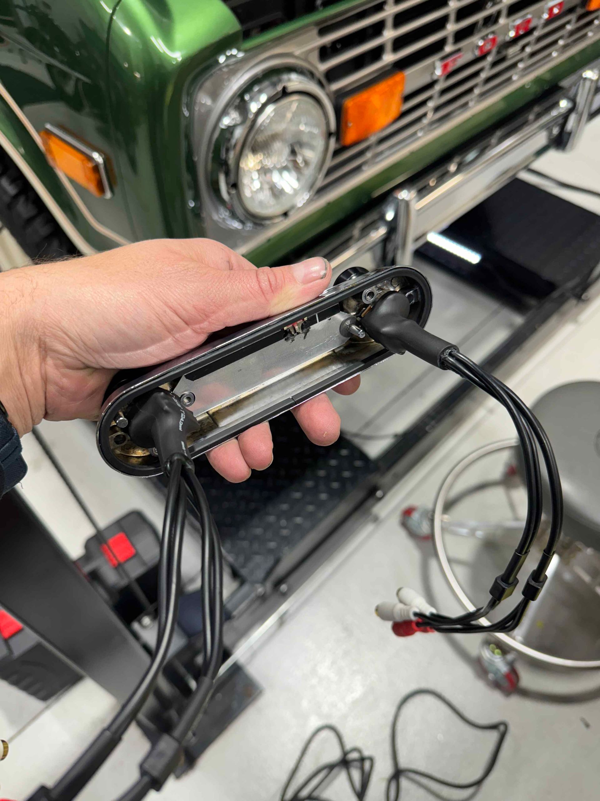 A person is holding a piece of metal in front of a green truck