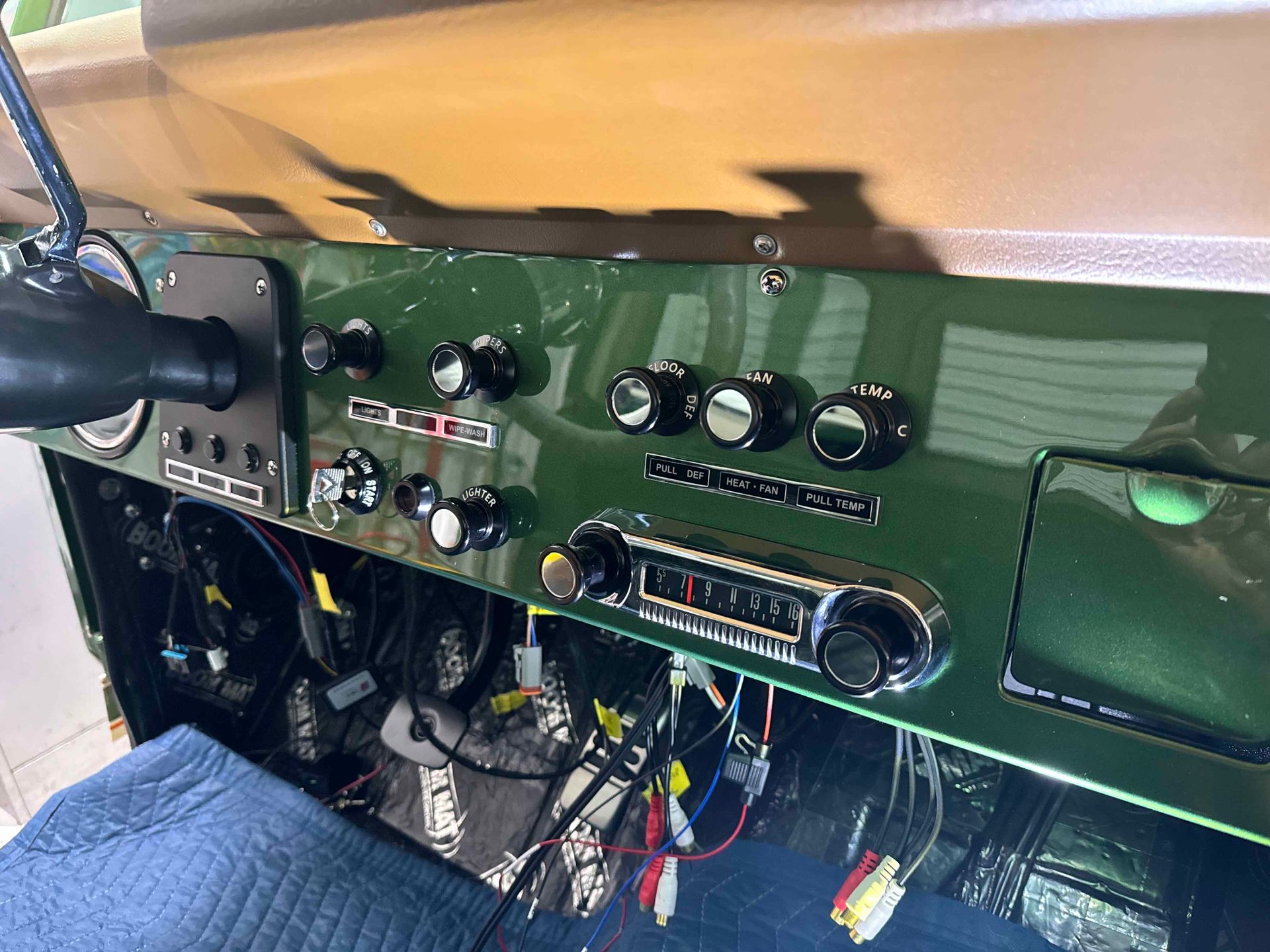 The dashboard of a green jeep with a radio and buttons.