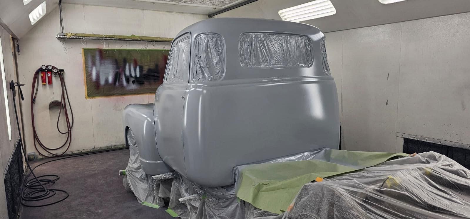 A truck is being painted in a paint booth.