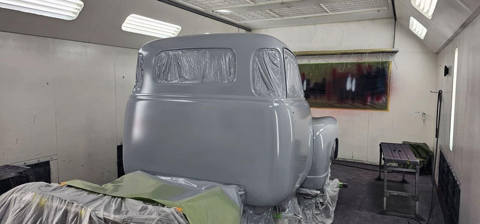 A truck is being painted in a paint booth.