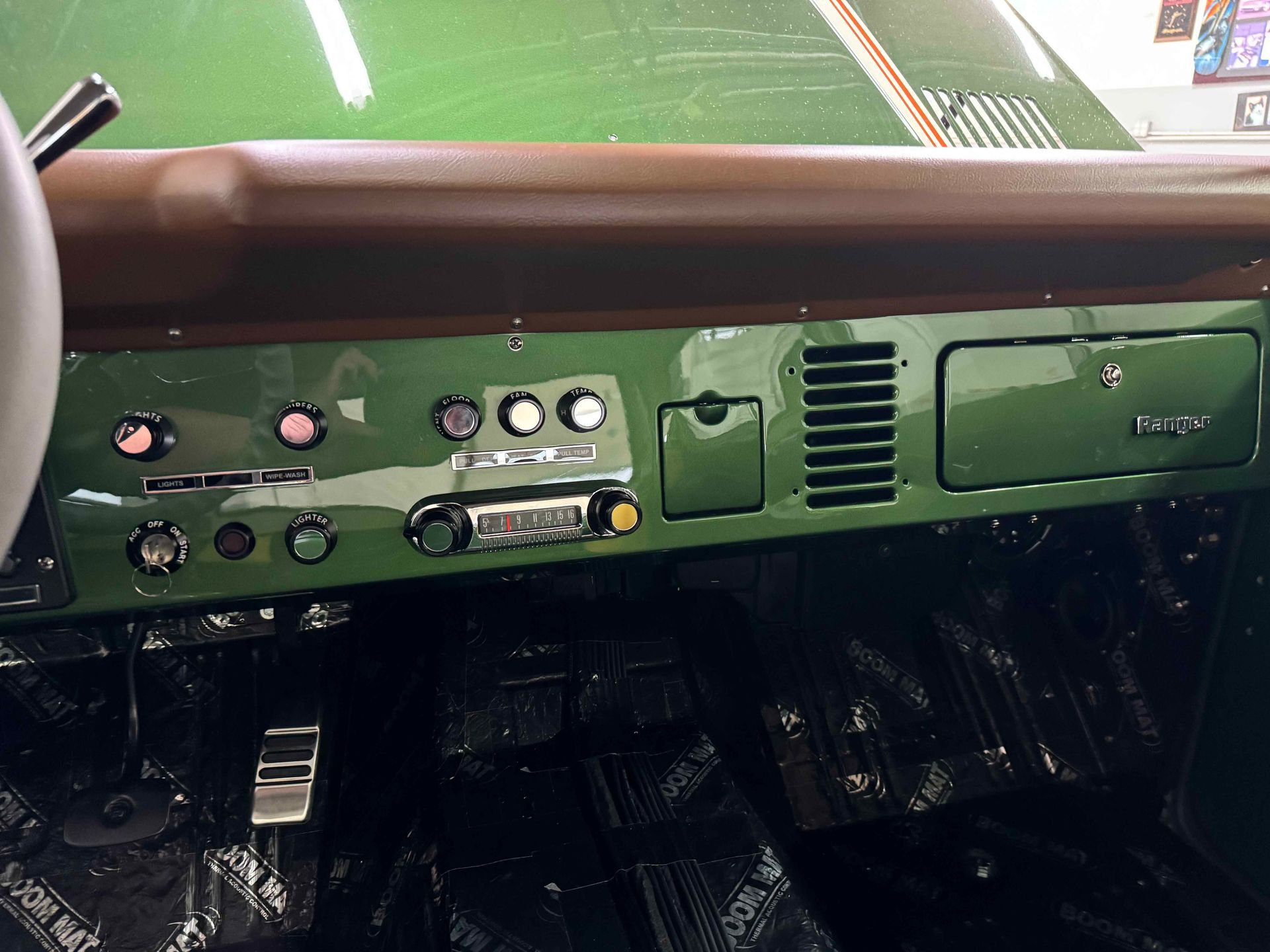 The dashboard of a green car with a brown trim.