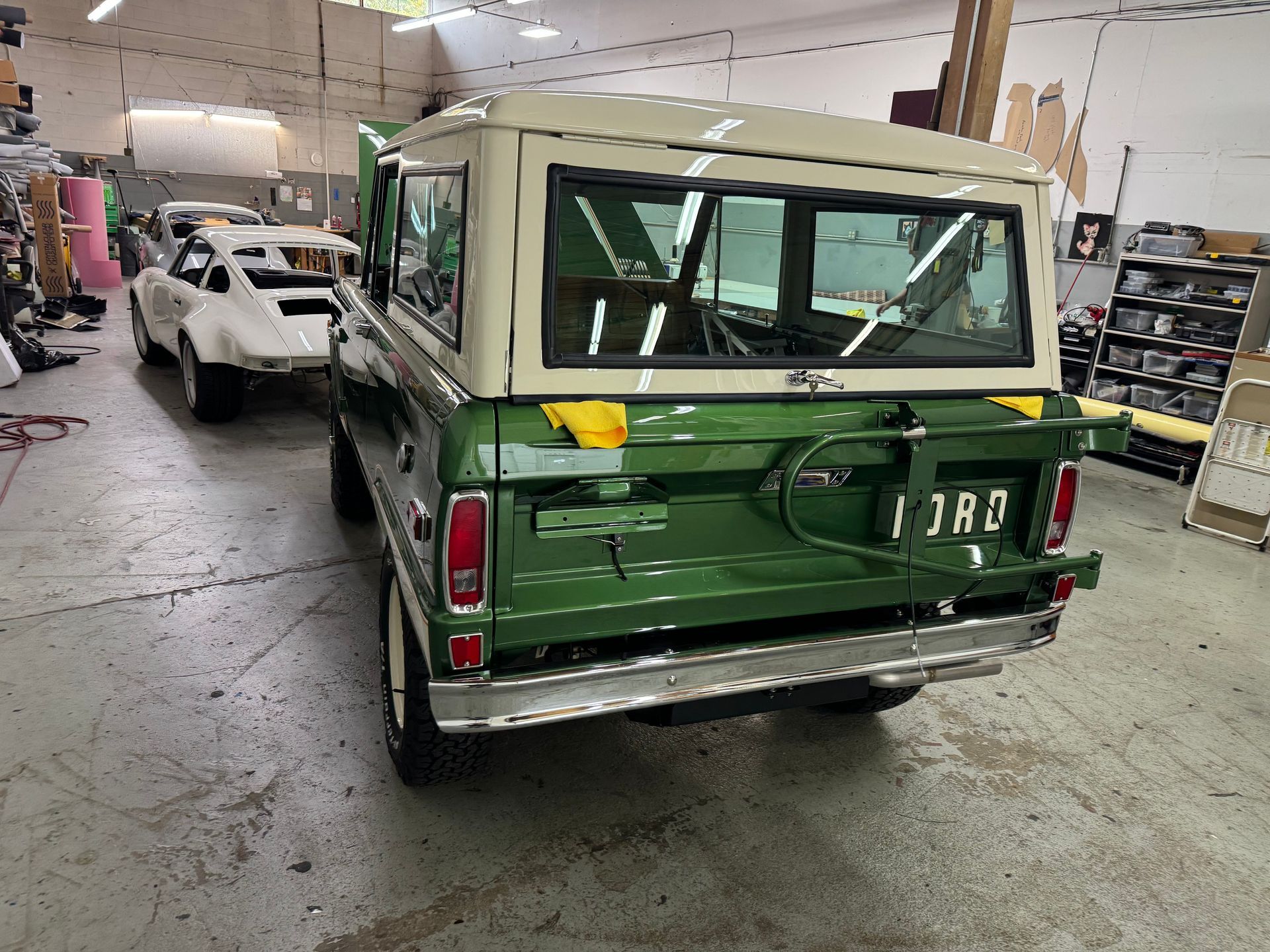 A green and white jeep is parked in a garage.