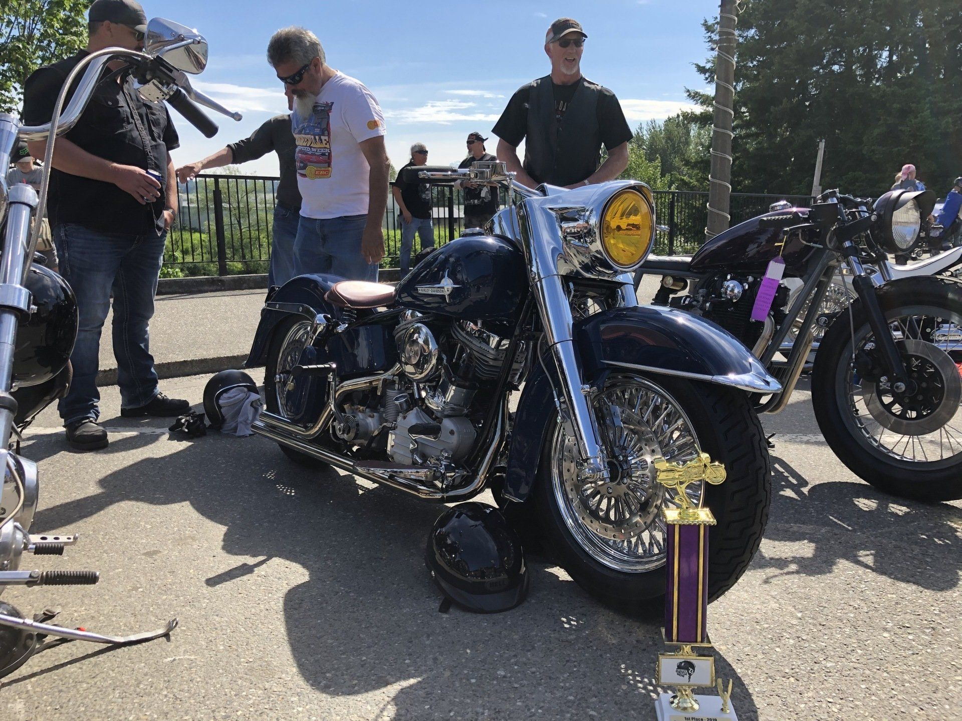 A group of men are standing around a motorcycle parked on the side of the road.