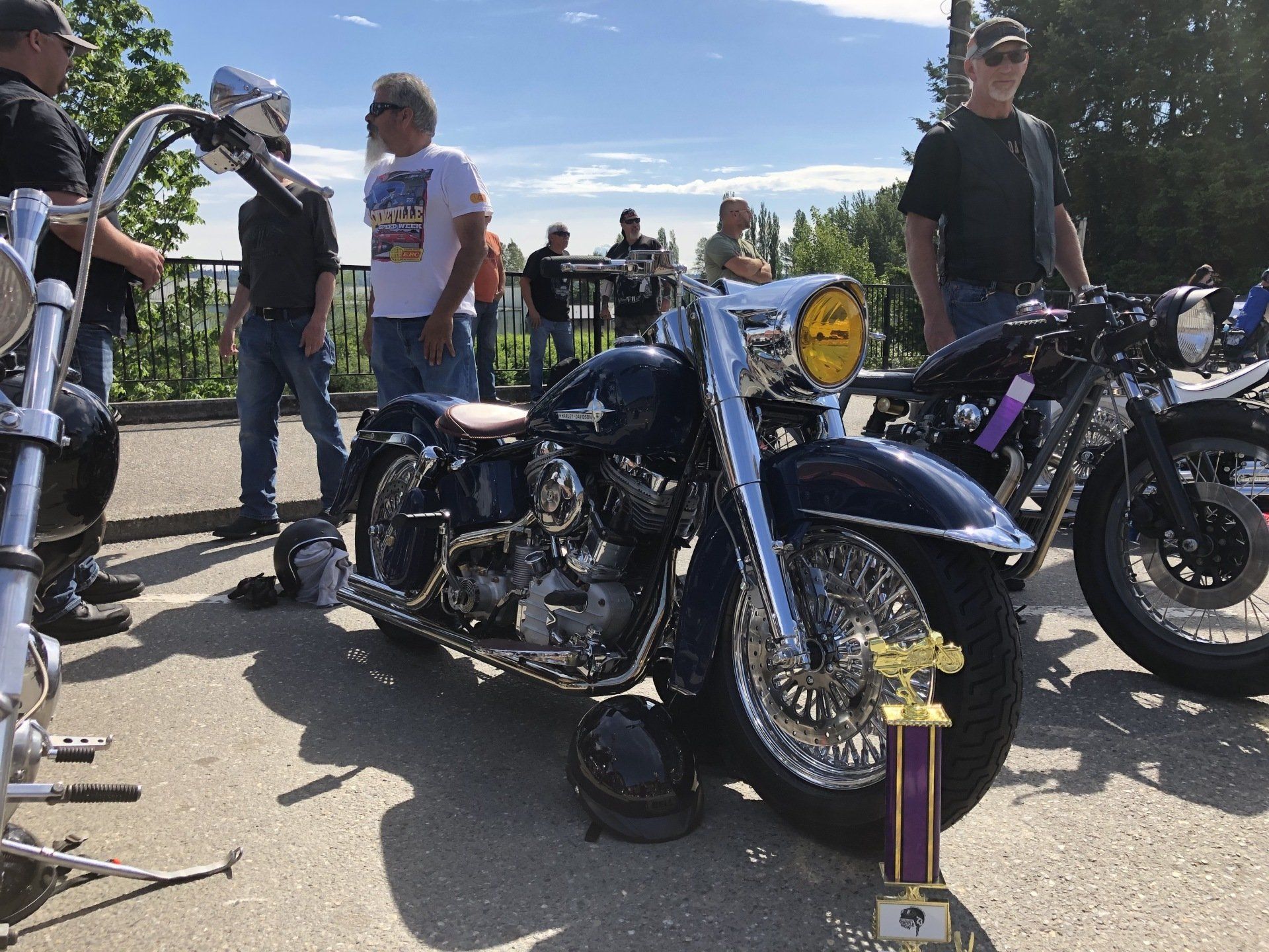 A motorcycle is parked next to a trophy on the side of the road.