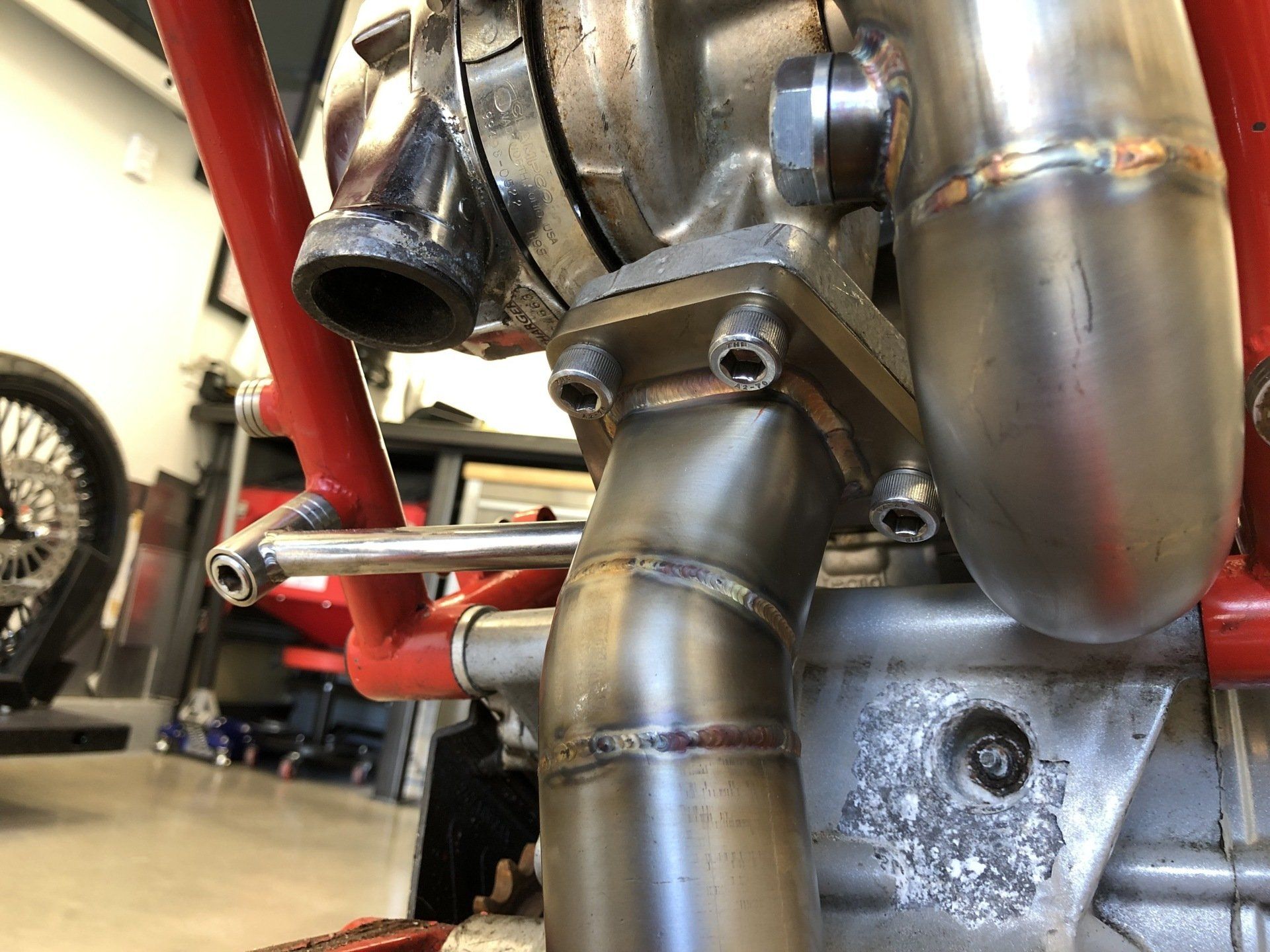 A close up of a stainless steel pipe on a motorcycle engine.