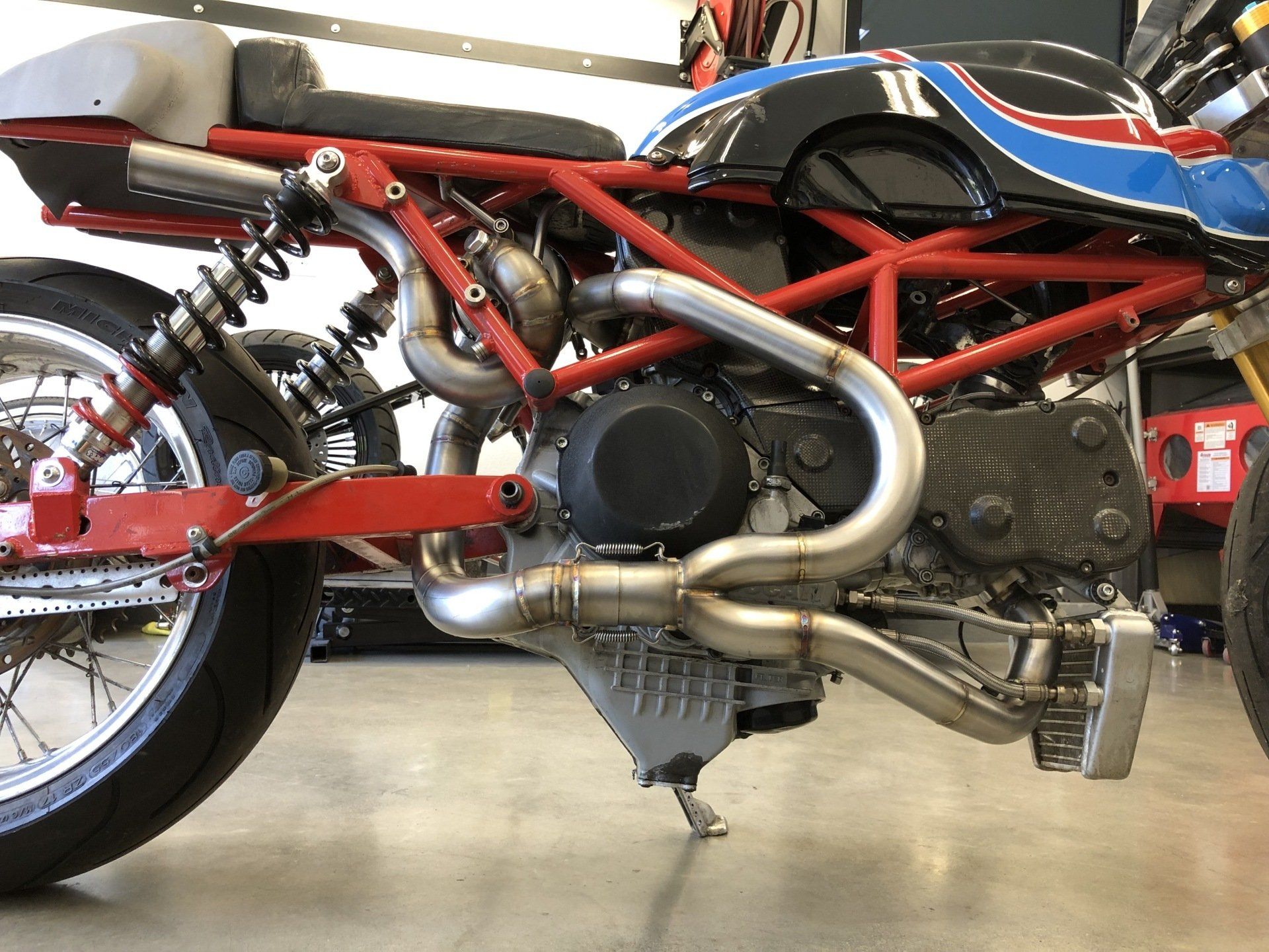A red and blue motorcycle is parked in a garage.
