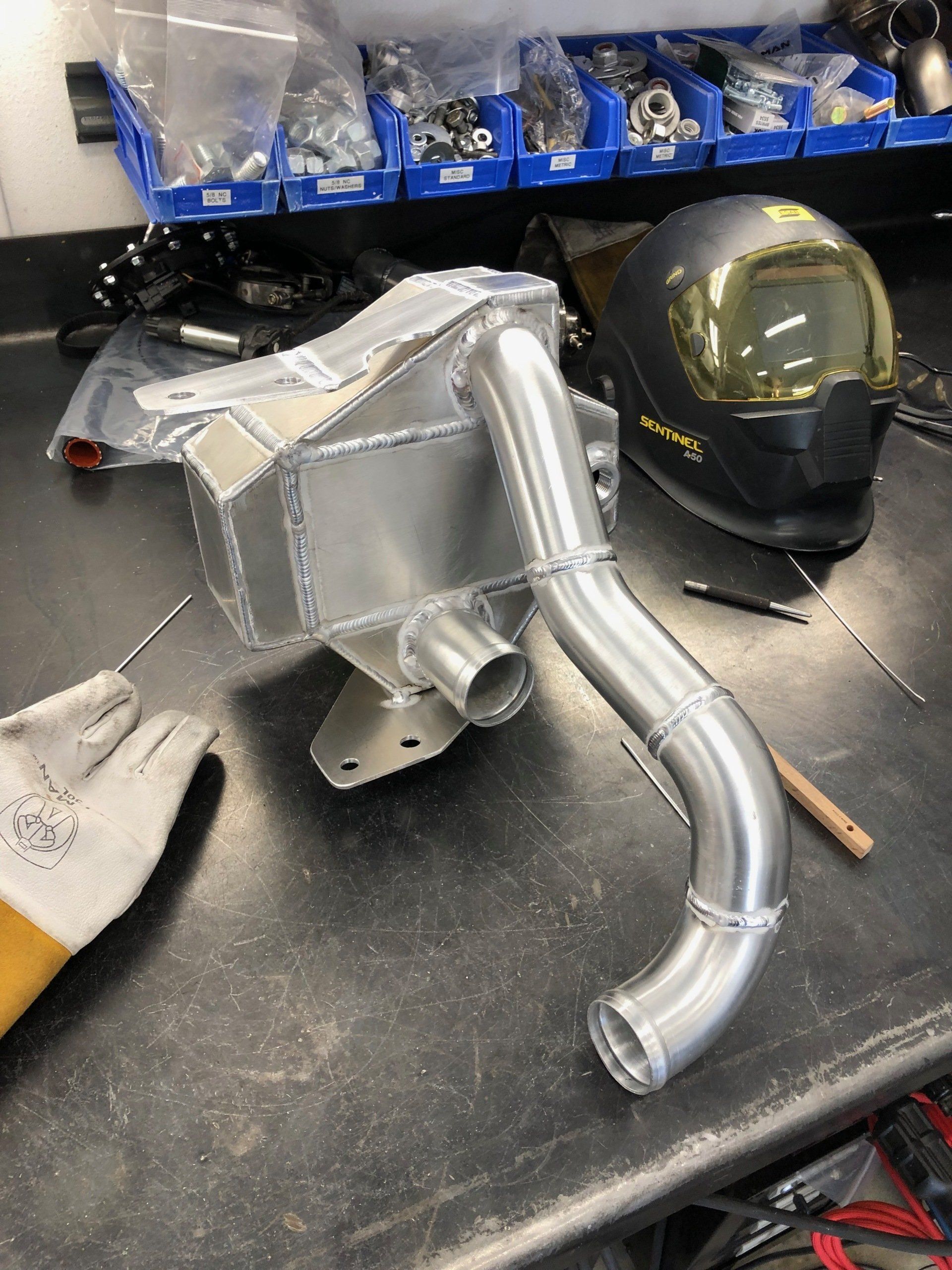 A metal pipe is sitting on a table next to a welding helmet.