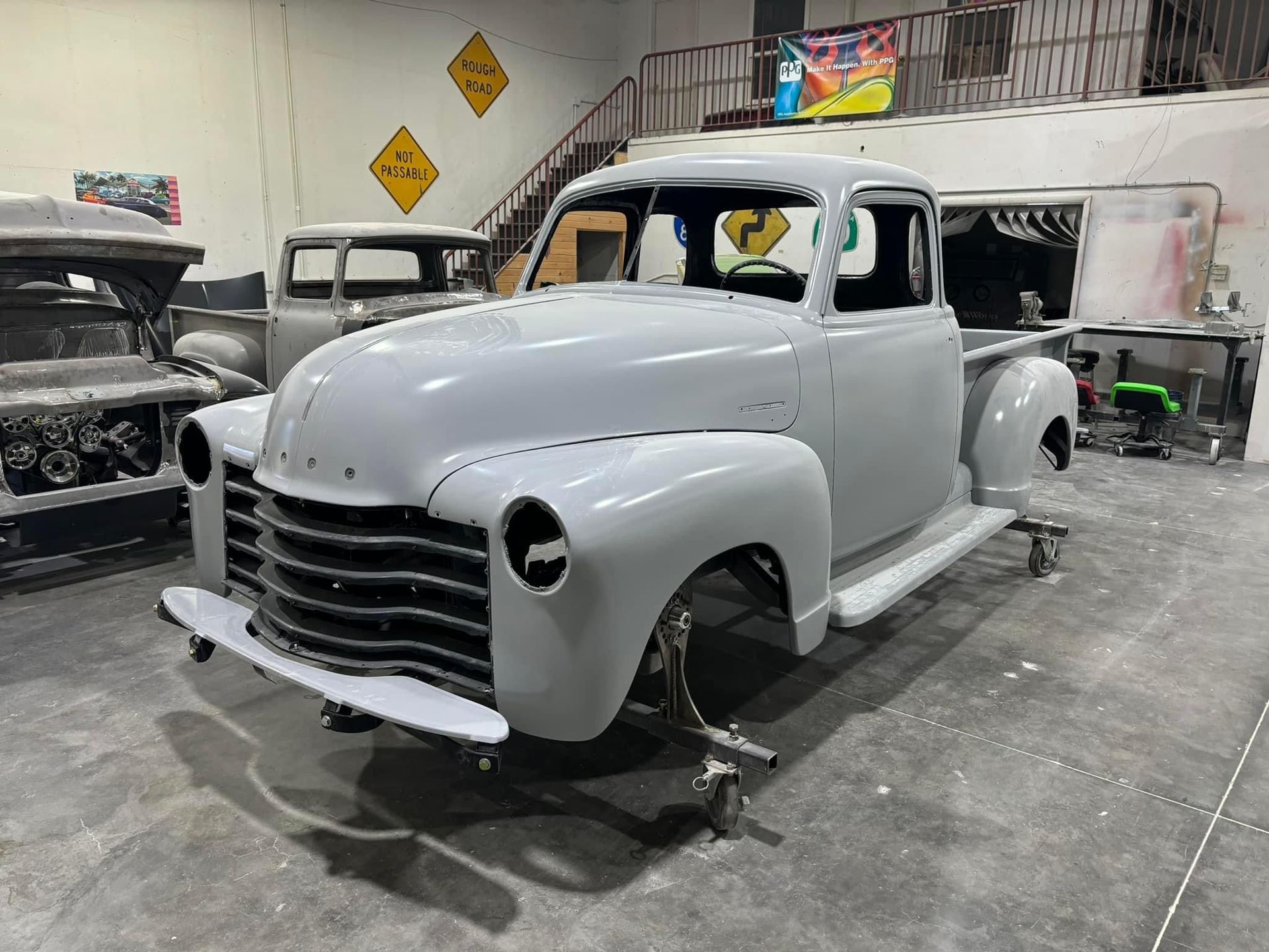 A white truck is sitting on wheels in a garage.