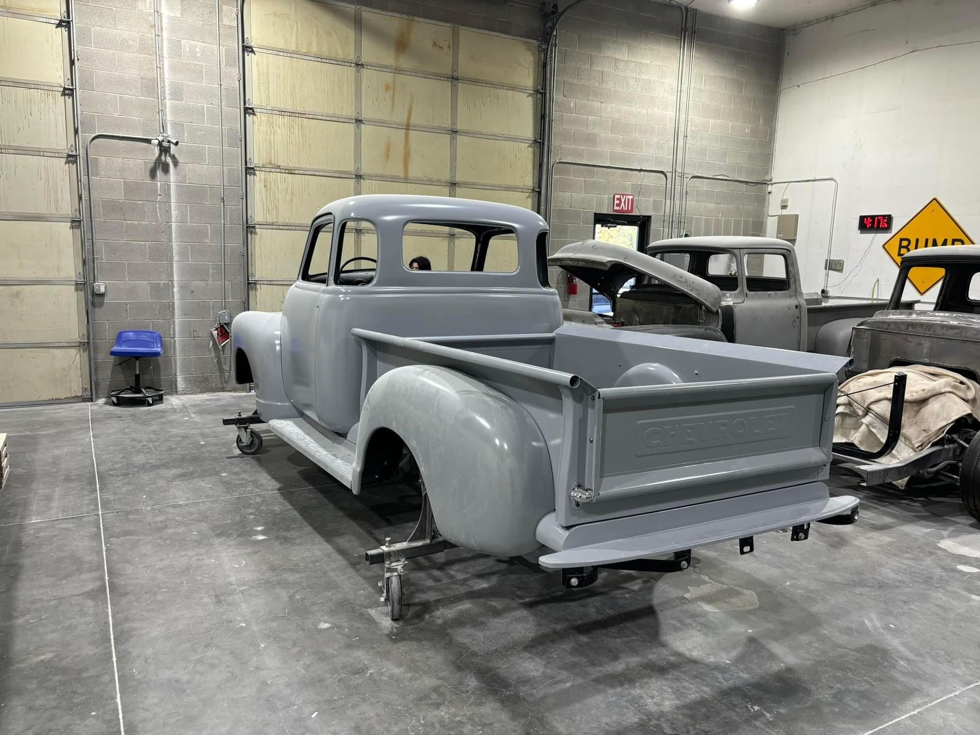 A gray truck is sitting in a garage with other trucks.