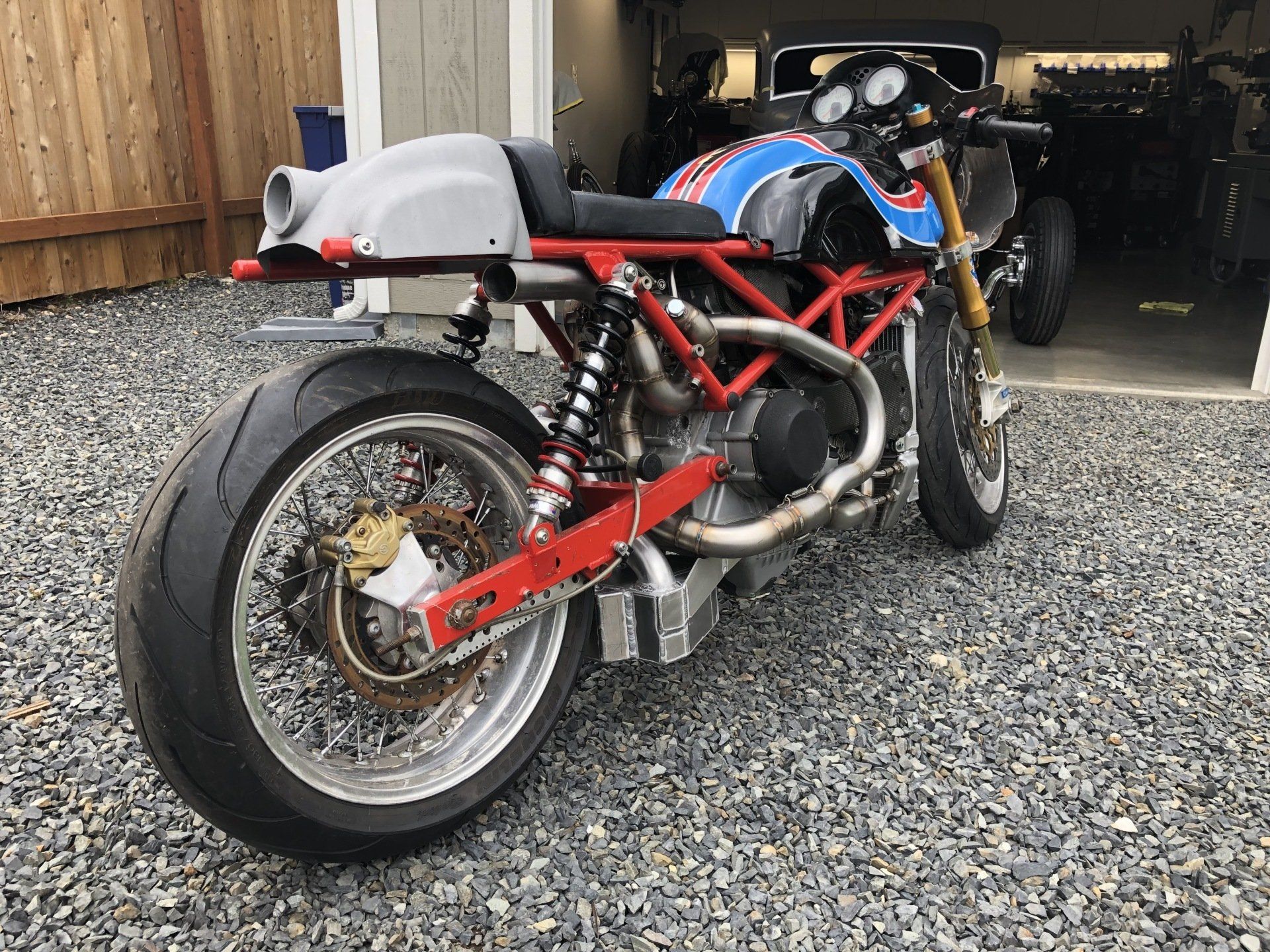 A motorcycle is parked on gravel in front of a garage.