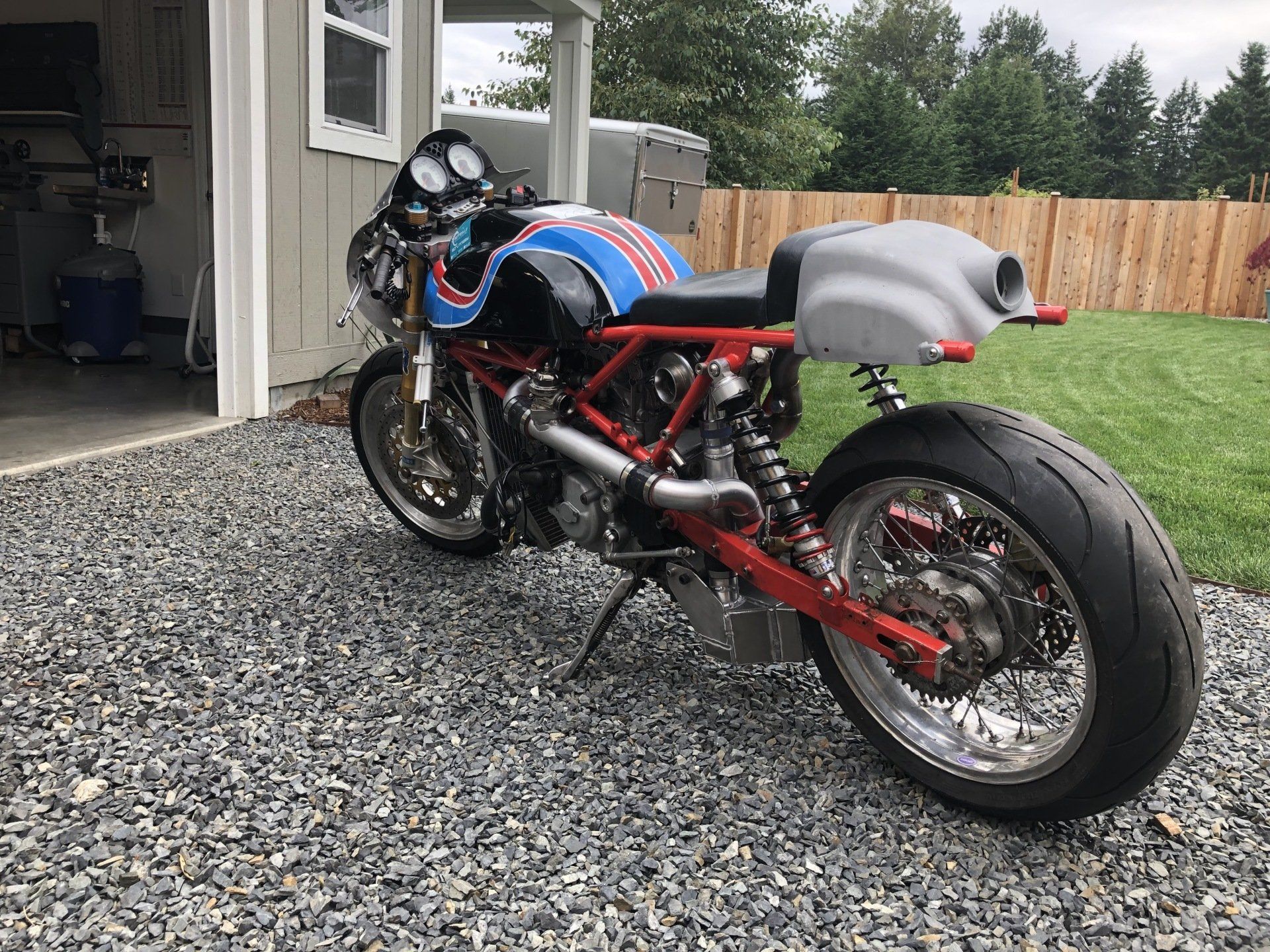 A motorcycle is parked on gravel in front of a garage.