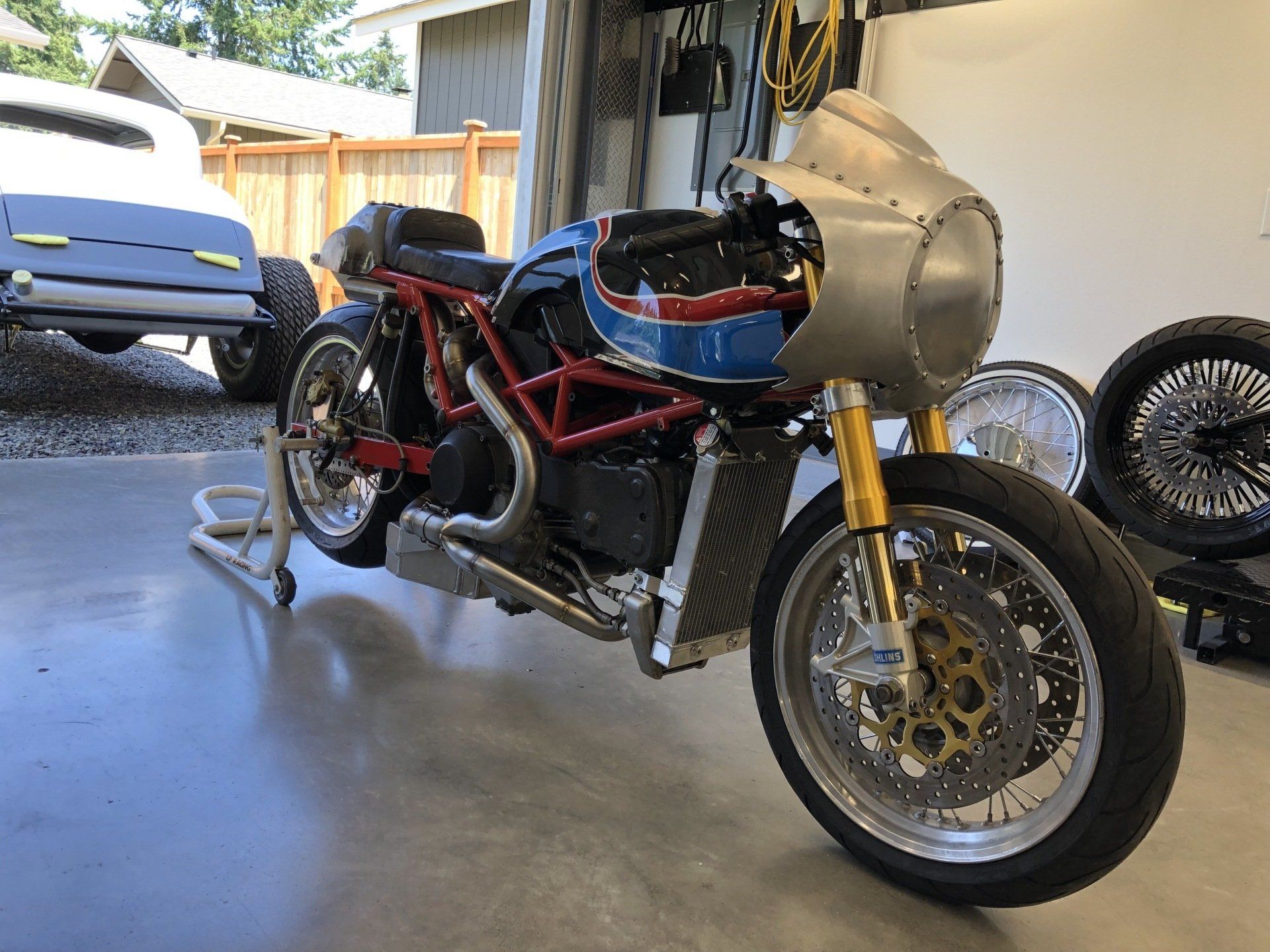 A motorcycle is parked in a garage next to a trailer.