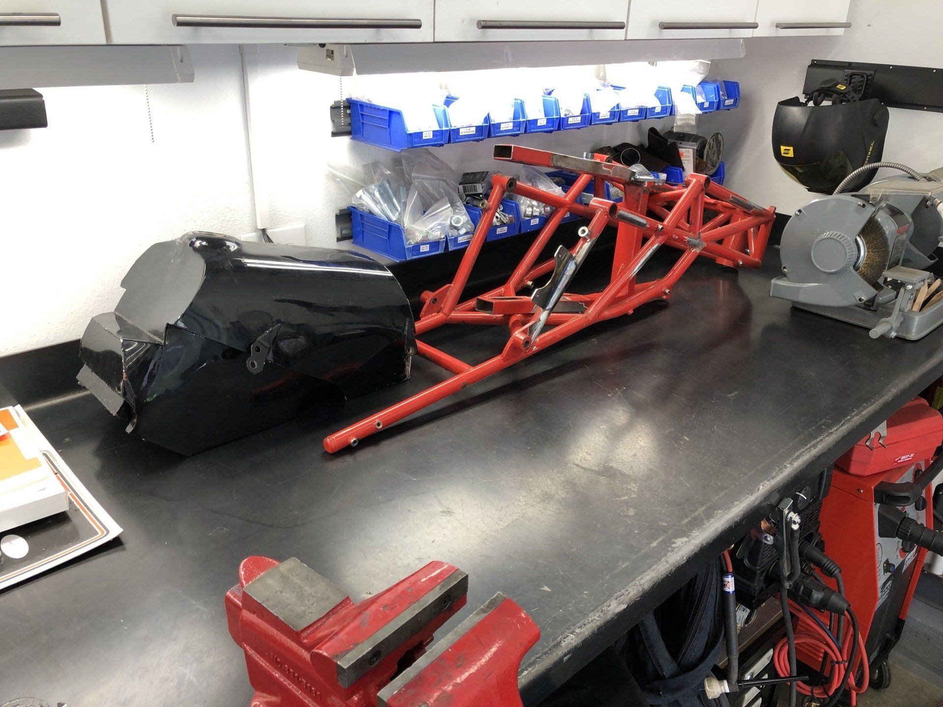 A motorcycle frame is sitting on a workbench in a garage.