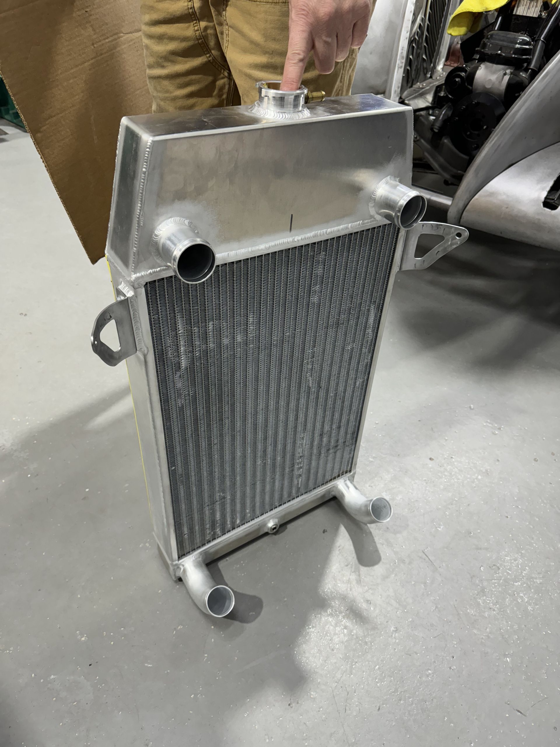 A person is holding a radiator on a concrete floor.