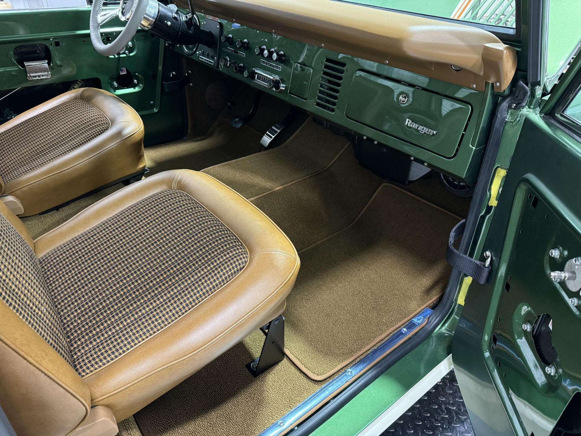 The interior of a green car with brown seats and a steering wheel.