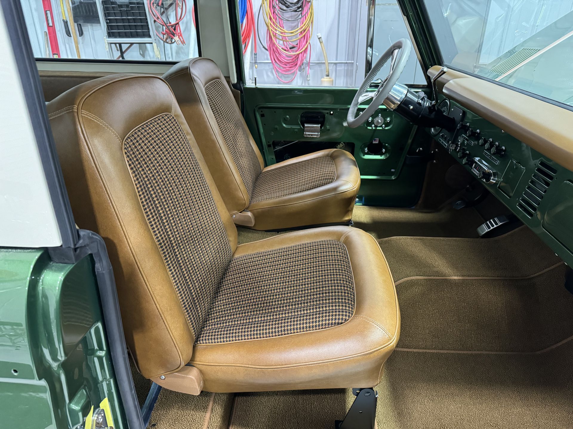 The interior of a green truck with brown seats and a steering wheel.