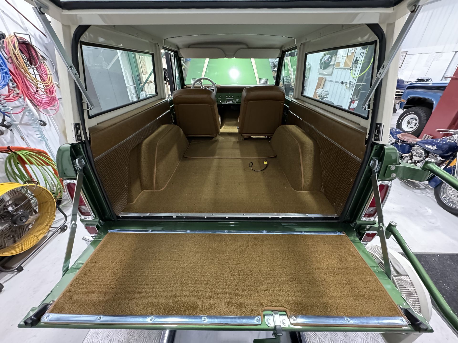 The back of a green and white jeep with the door open