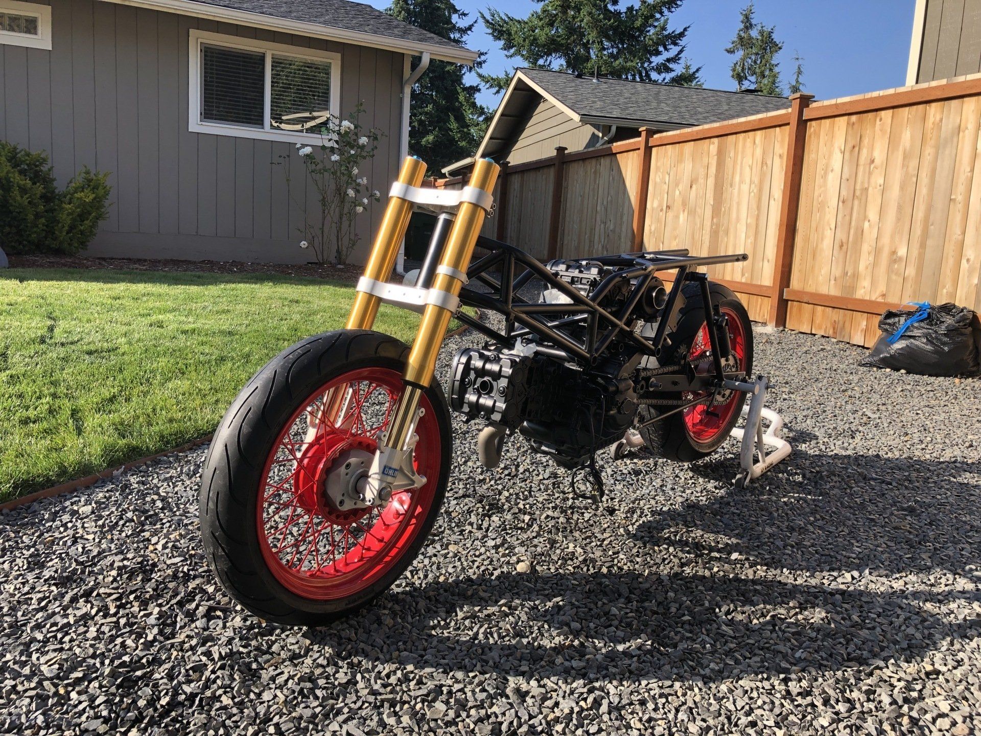 A motorcycle is parked on gravel in front of a house.
