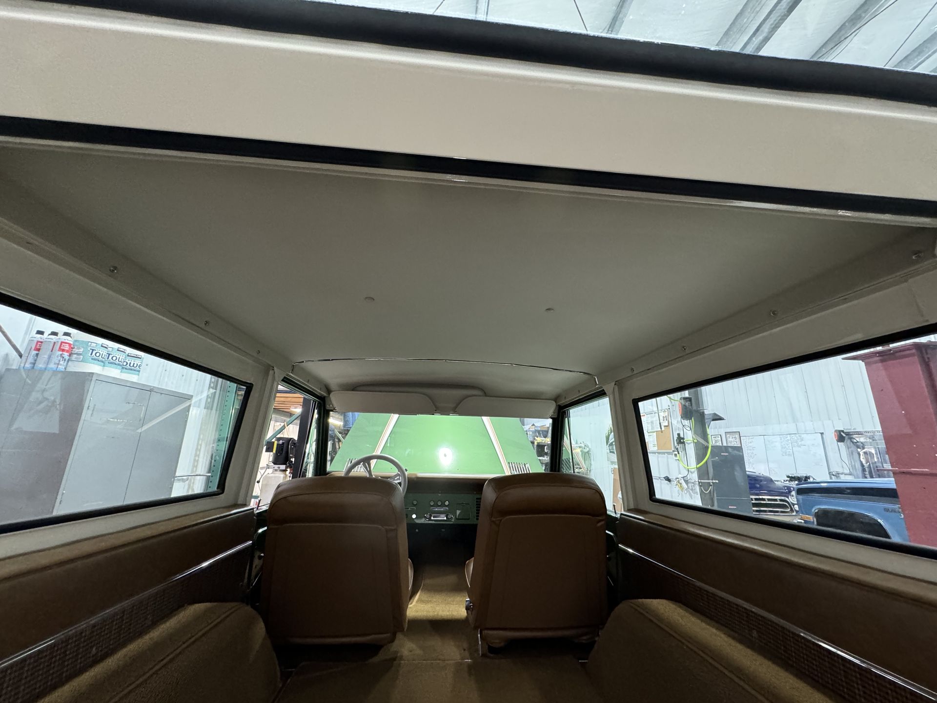 The inside of a van with brown seats and a white roof.