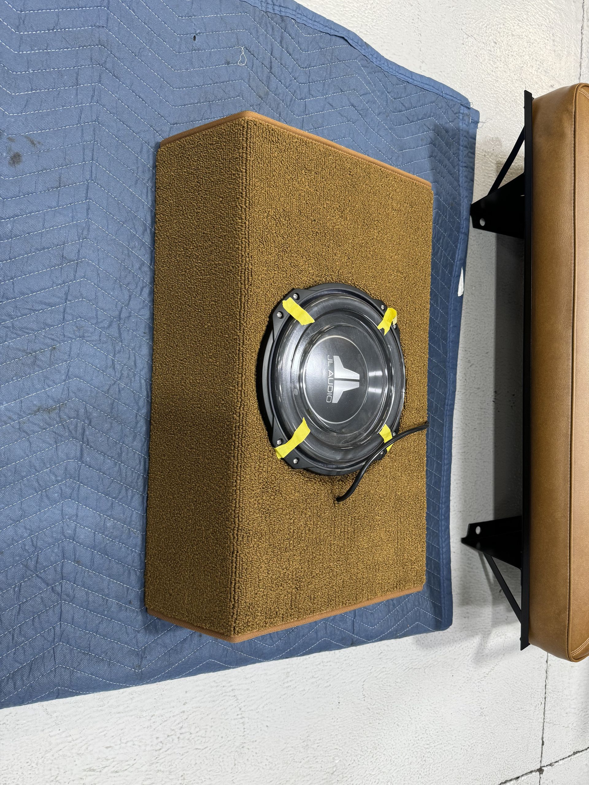 A subwoofer is sitting on top of a wooden box