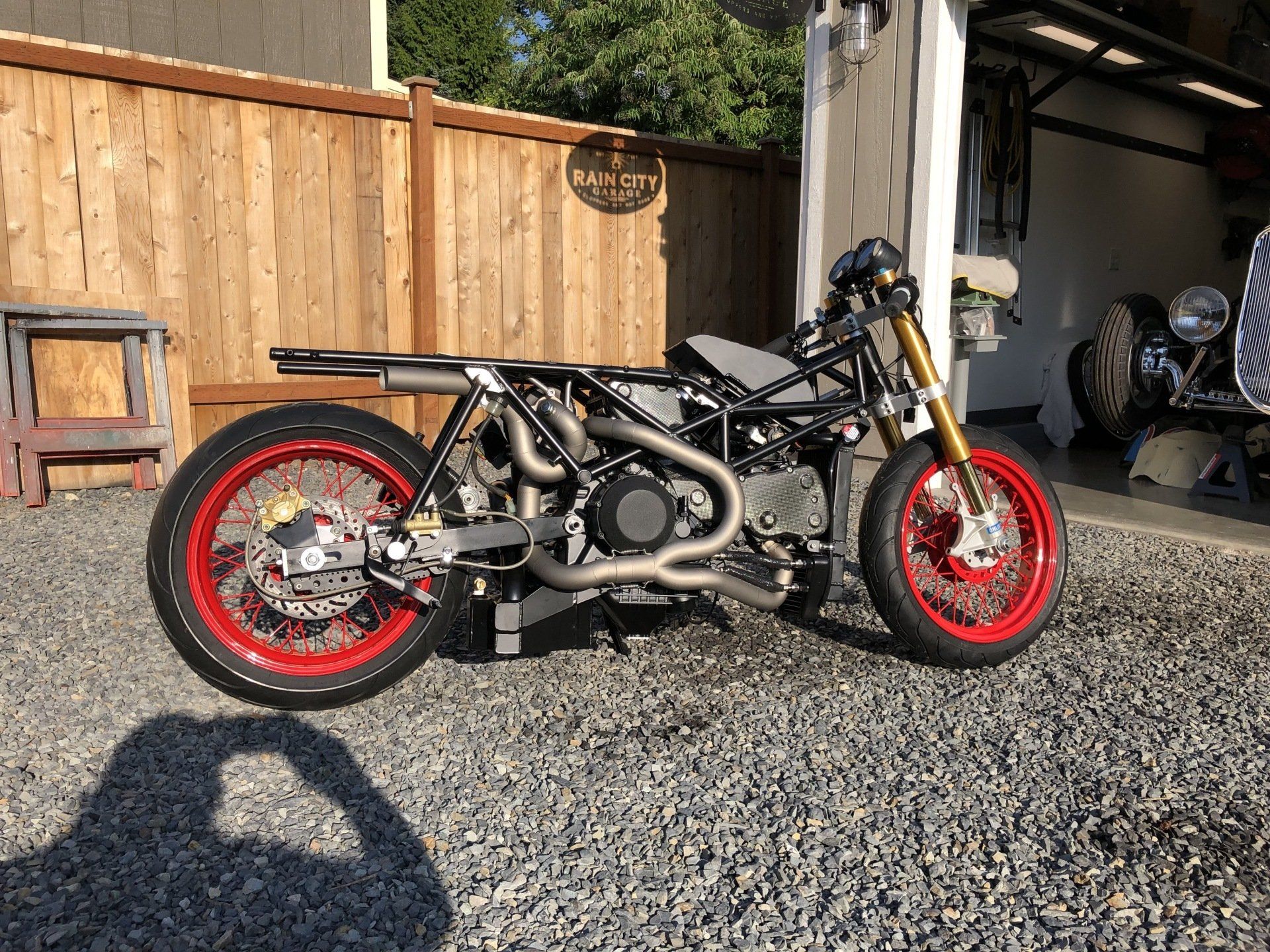 A motorcycle with red wheels is parked in front of a garage.