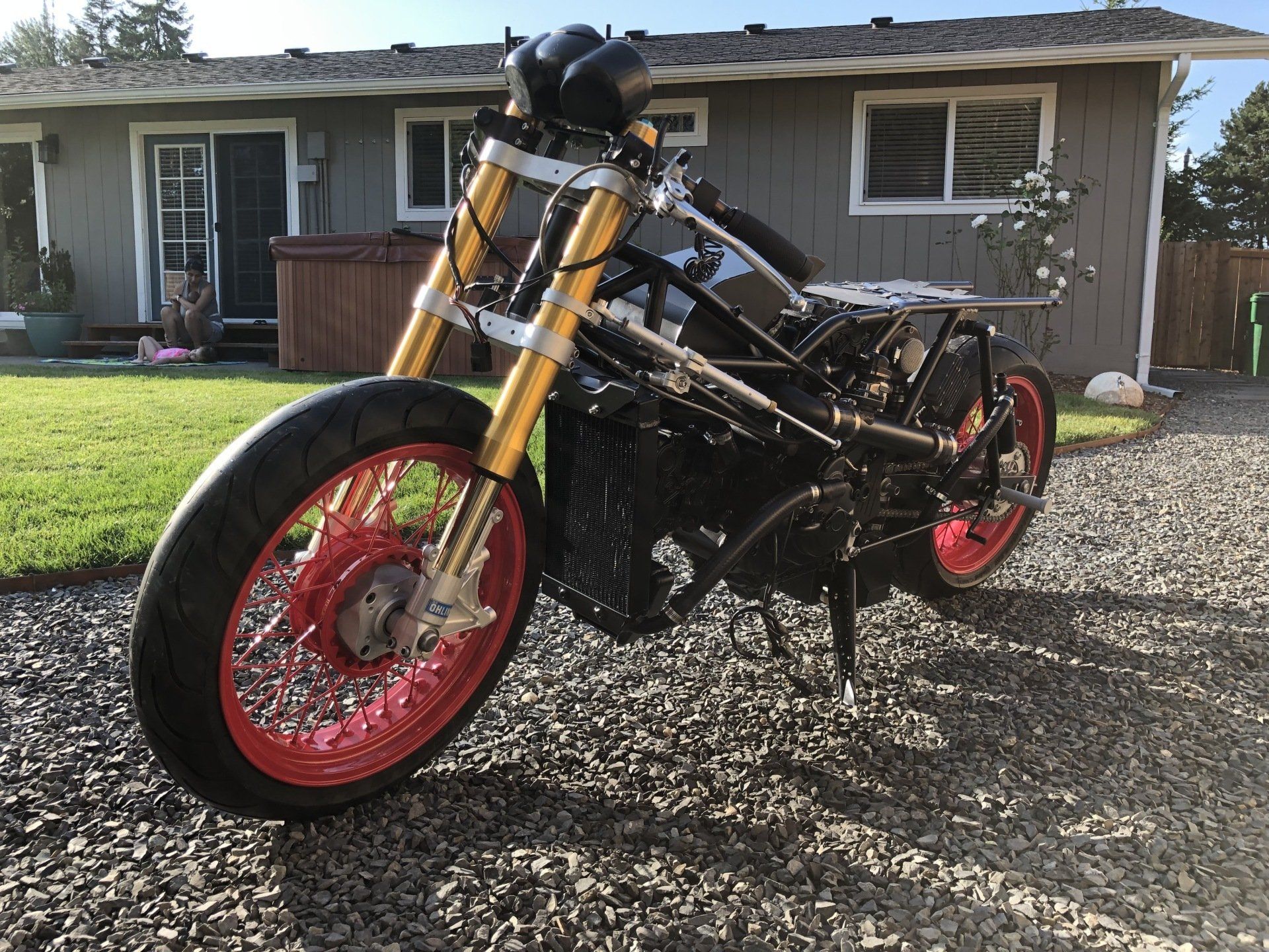 A motorcycle with red wheels is parked in front of a house.
