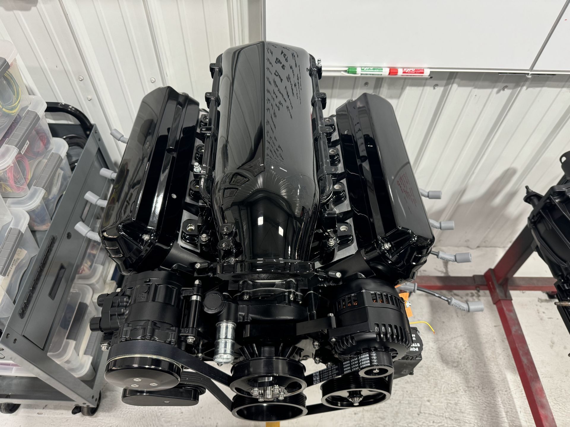 A black engine is sitting in a garage next to a white board.