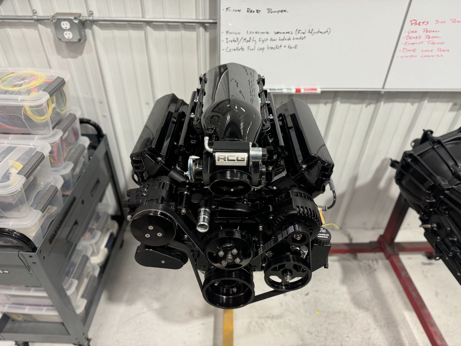 A black engine is sitting in front of a white board.