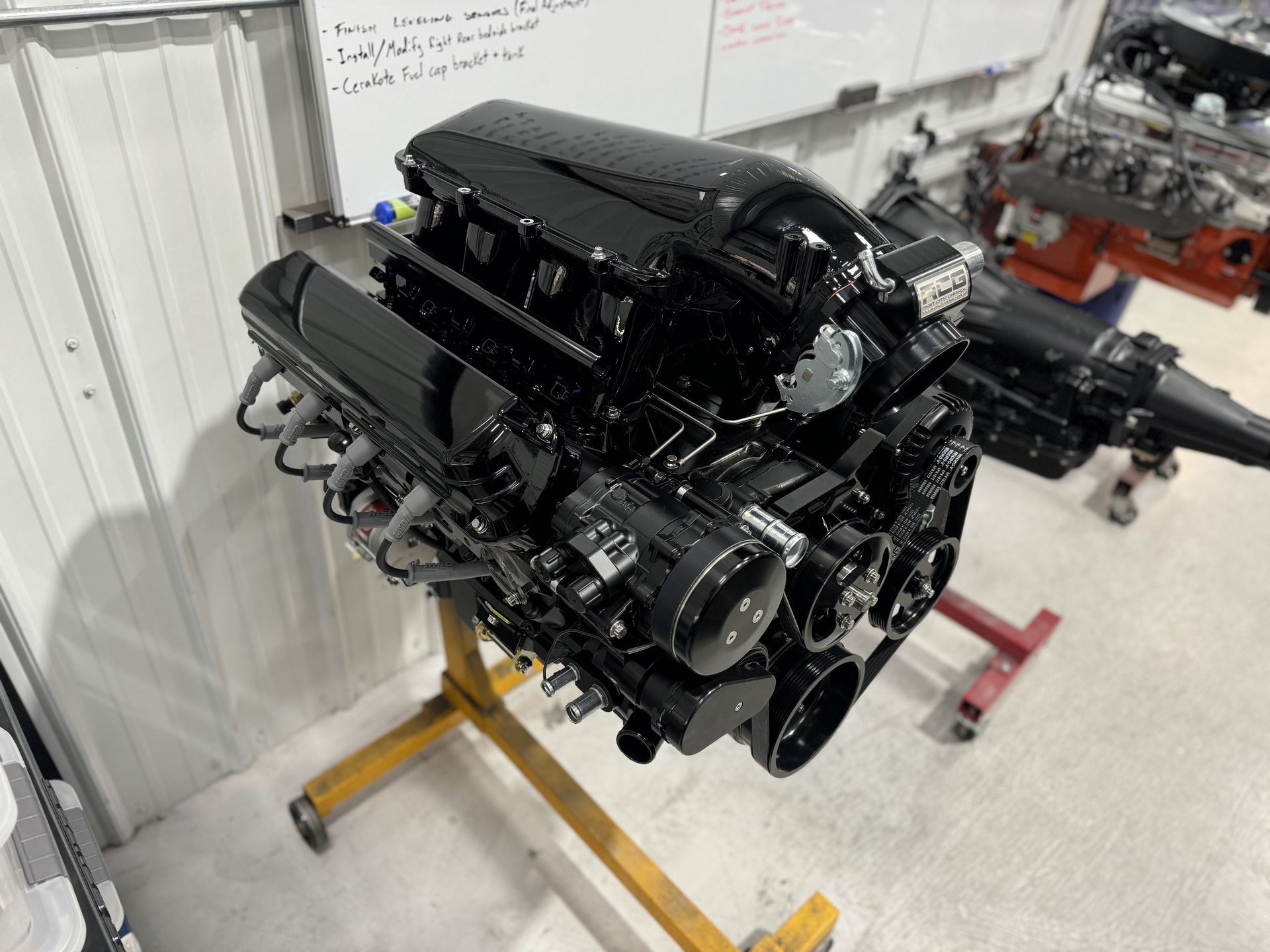A black engine is sitting on a yellow stand in a garage.