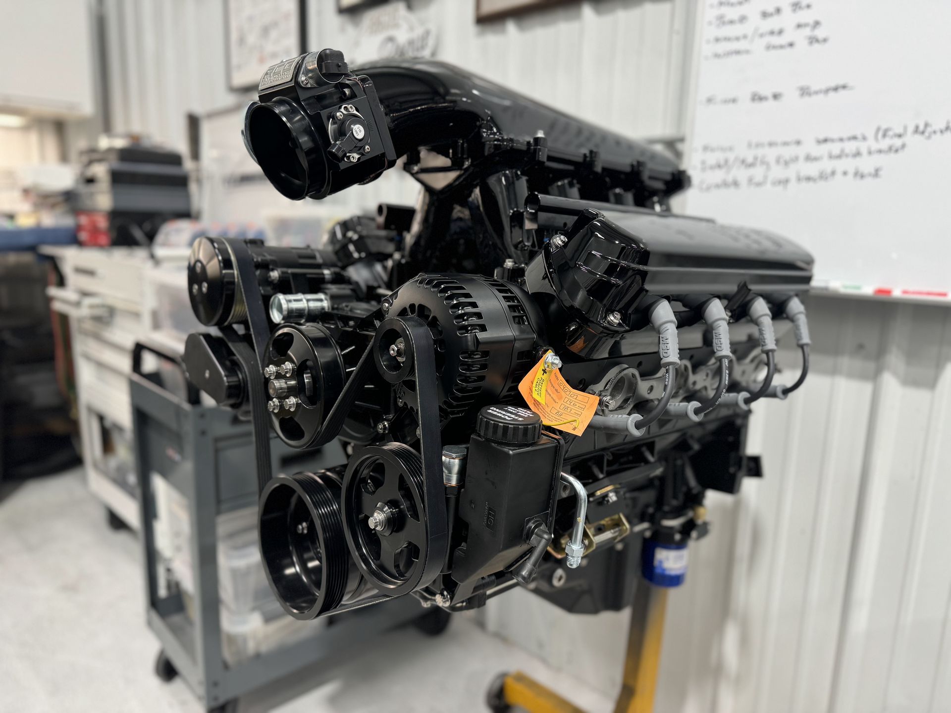 A black engine is sitting on a stand in a garage.