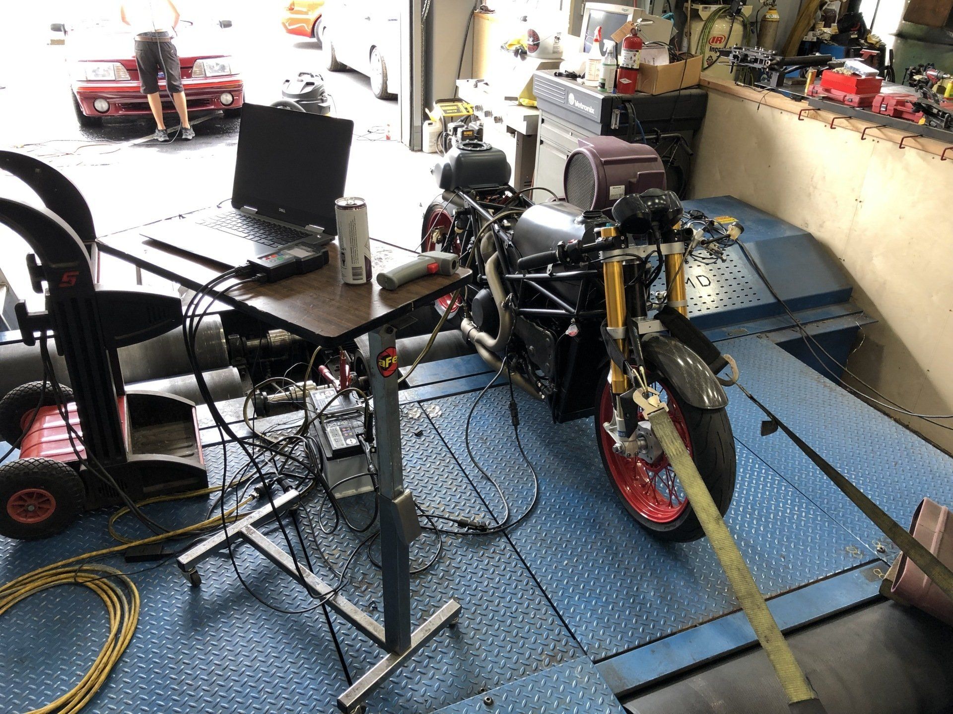 A motorcycle is tied to a table in a garage.