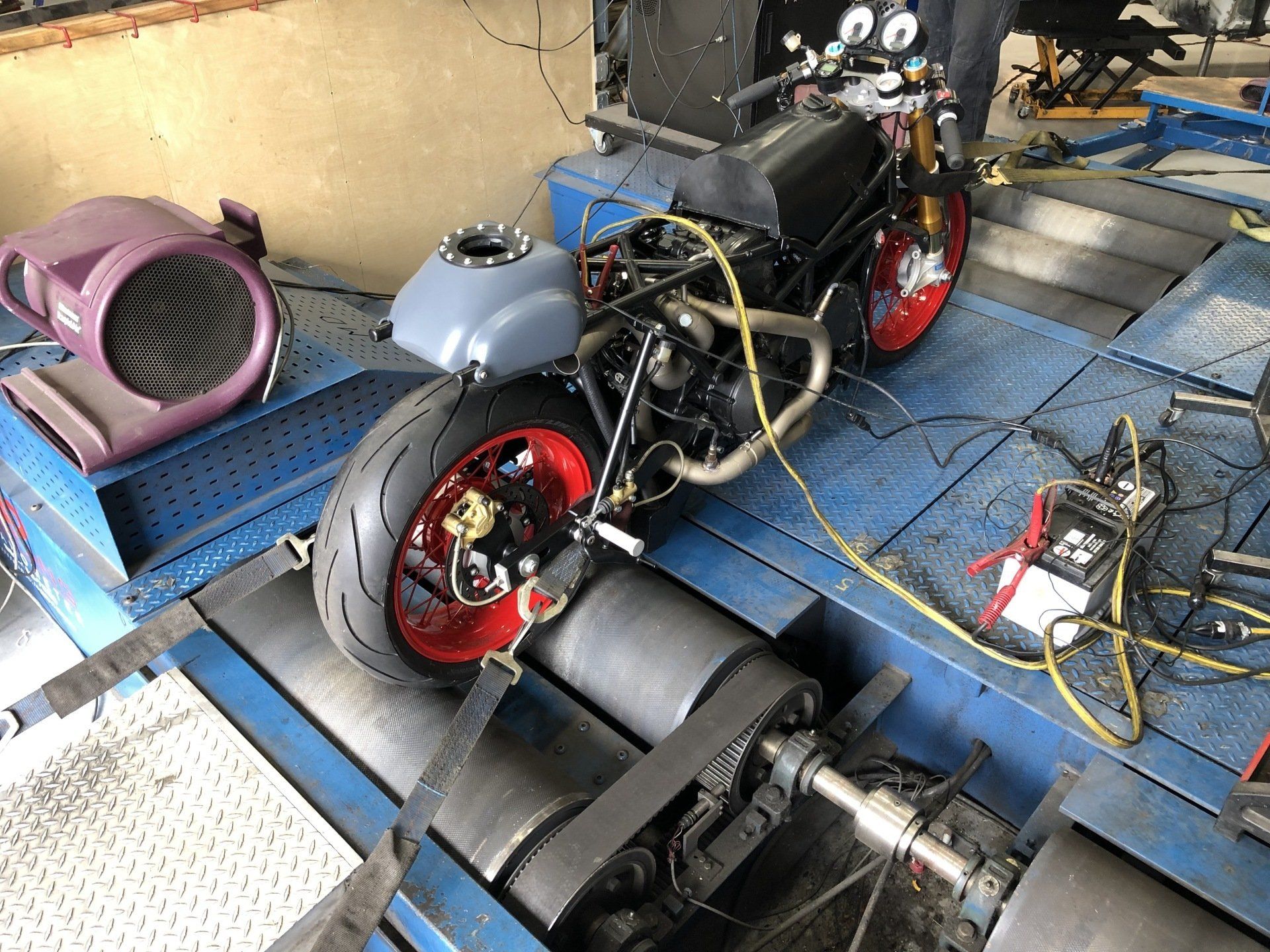 A motorcycle is being tested on a machine in a garage.