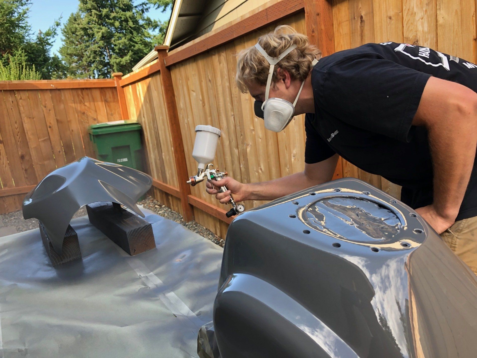 A man wearing a mask is spray painting a car.