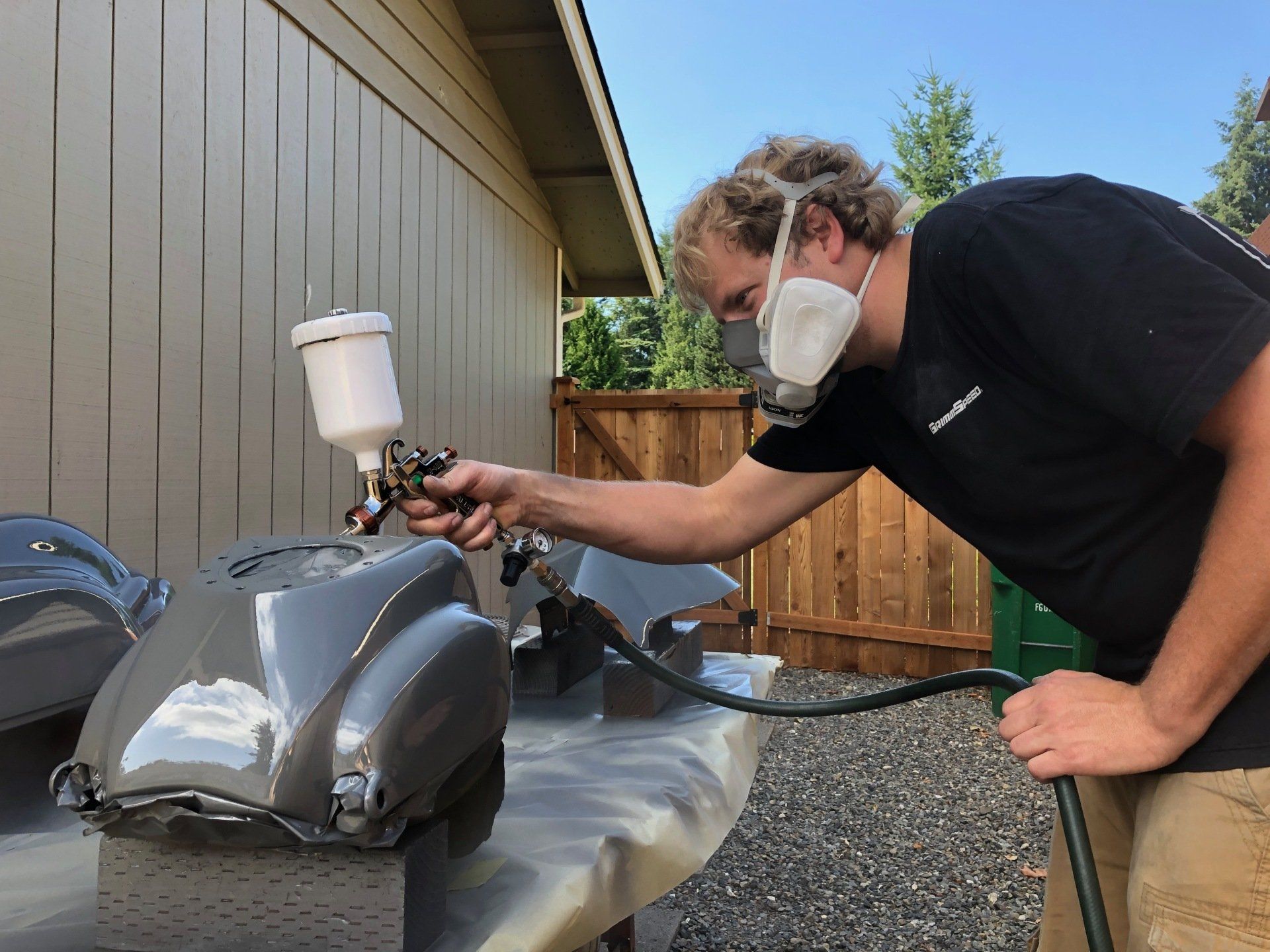 A man wearing a mask is spray painting a vehicle