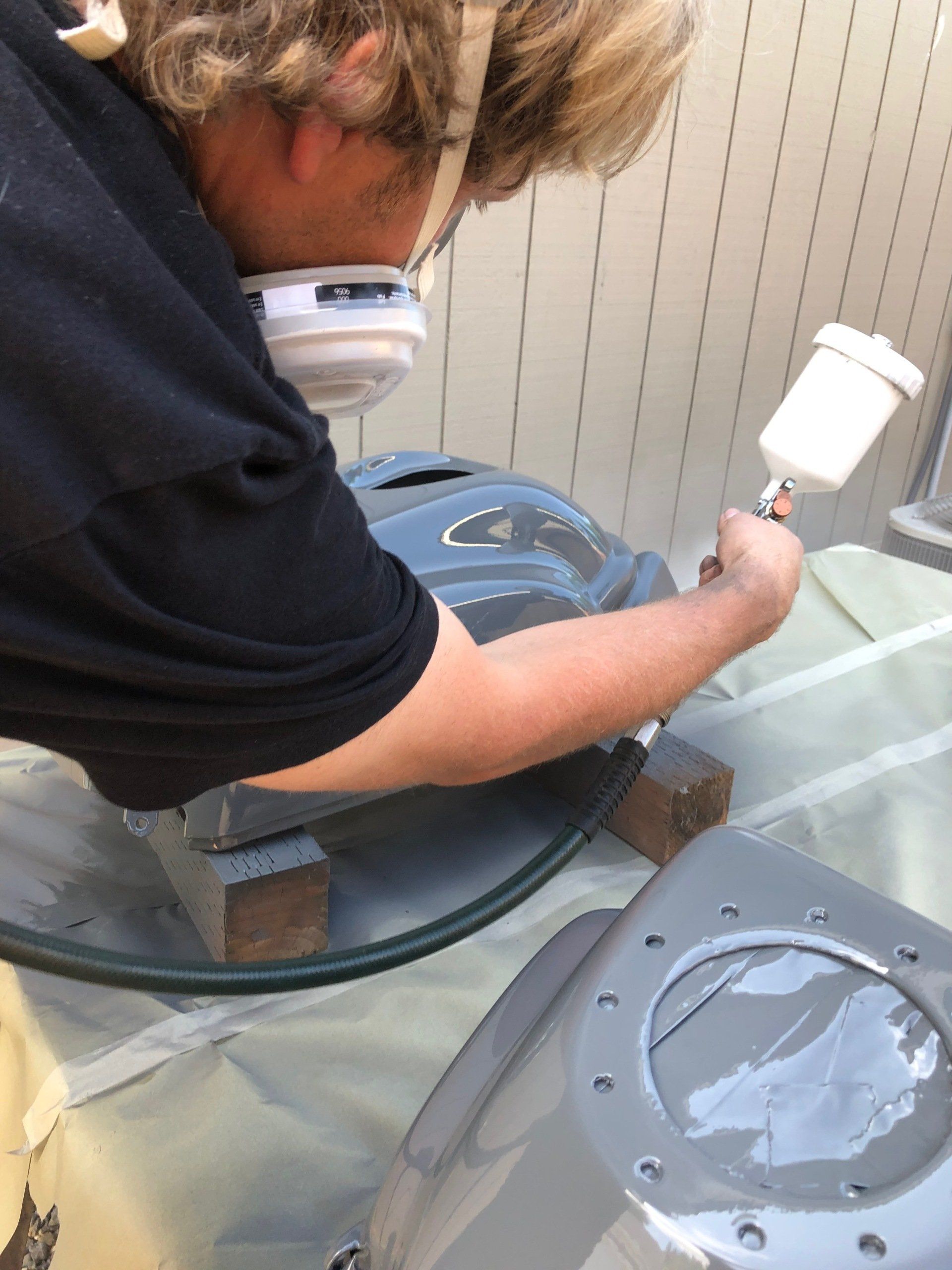 A man wearing a mask is painting a glass table