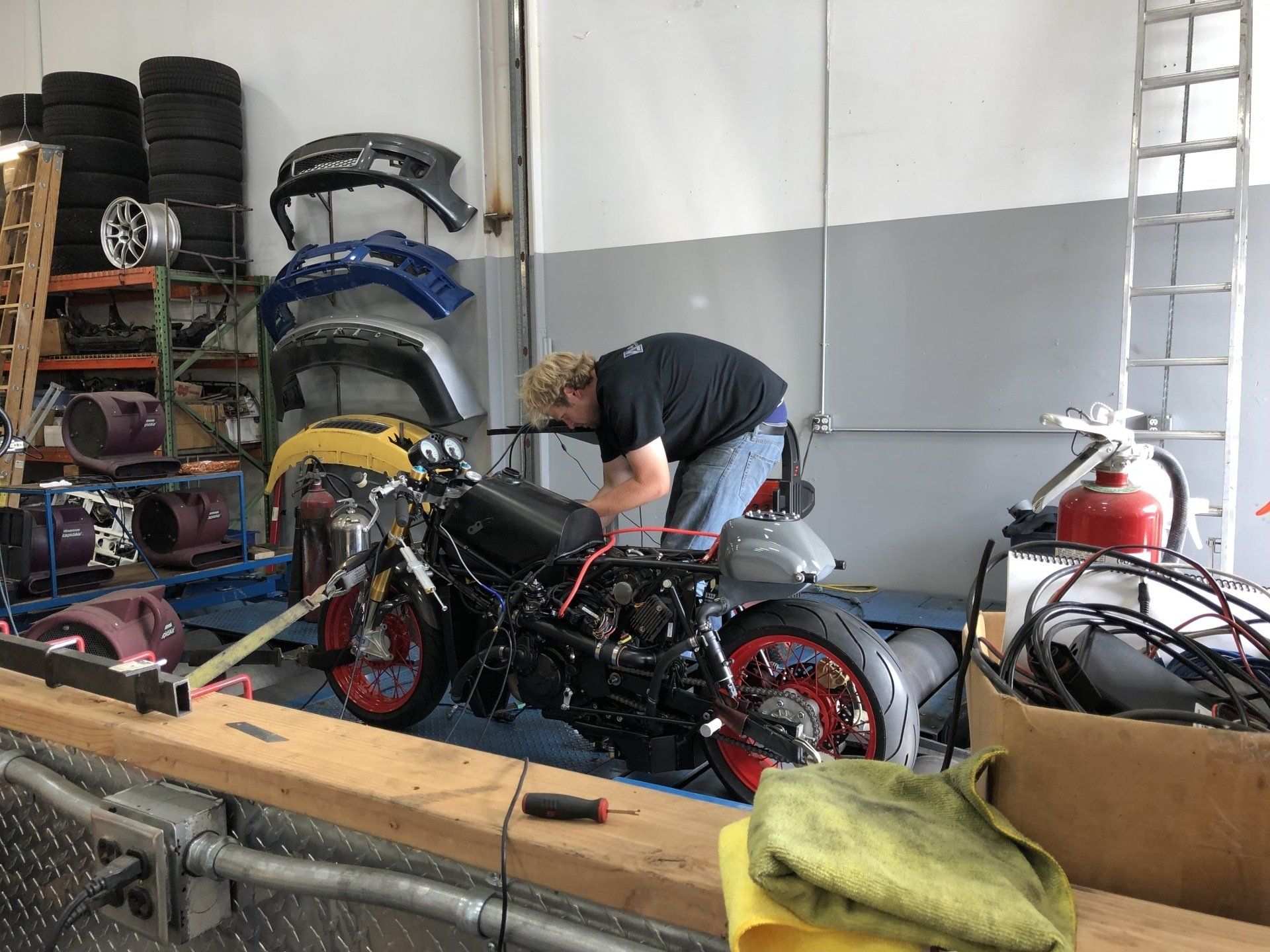 A man is working on a motorcycle in a garage.