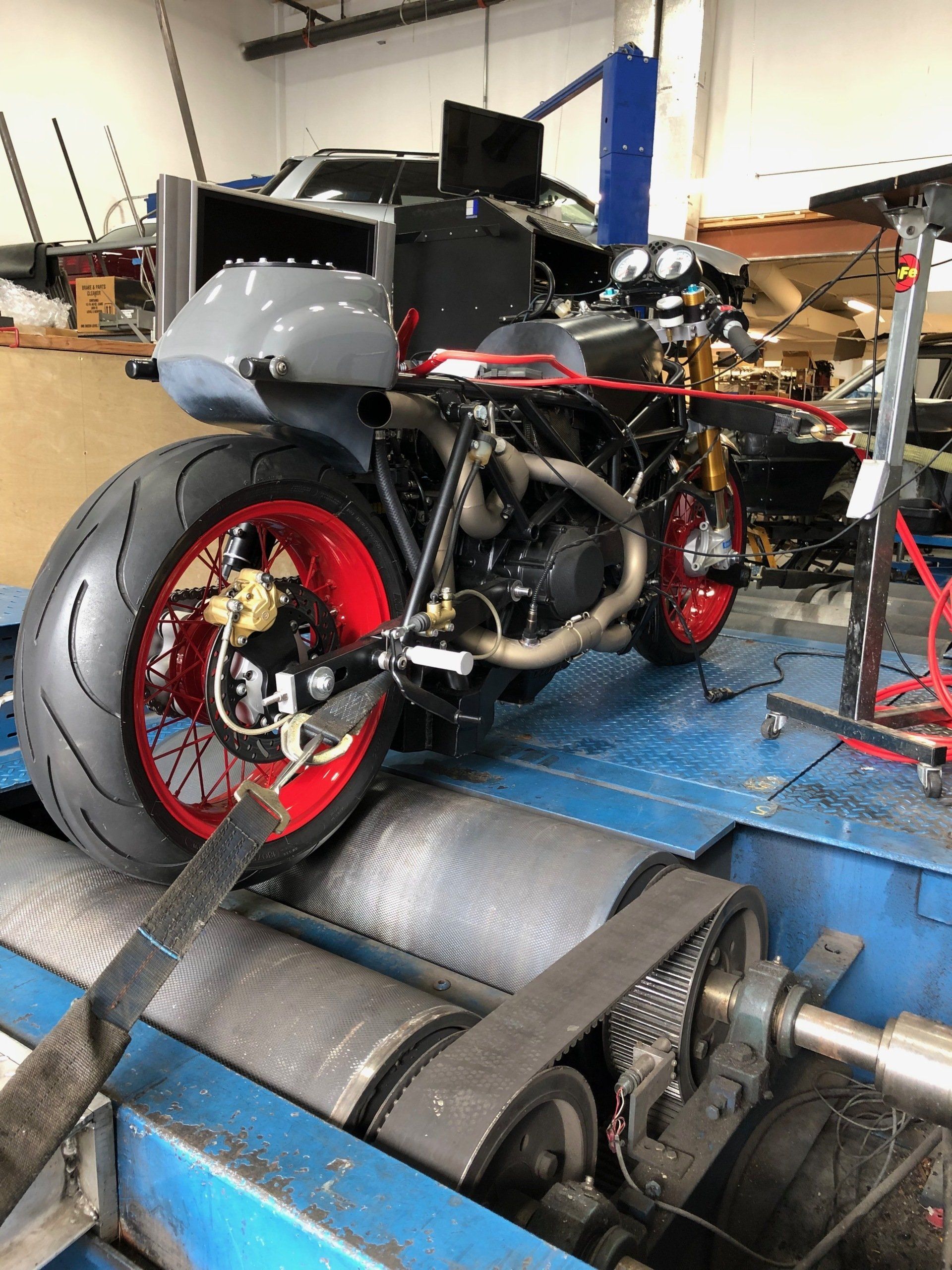 A motorcycle is sitting on a machine in a garage.