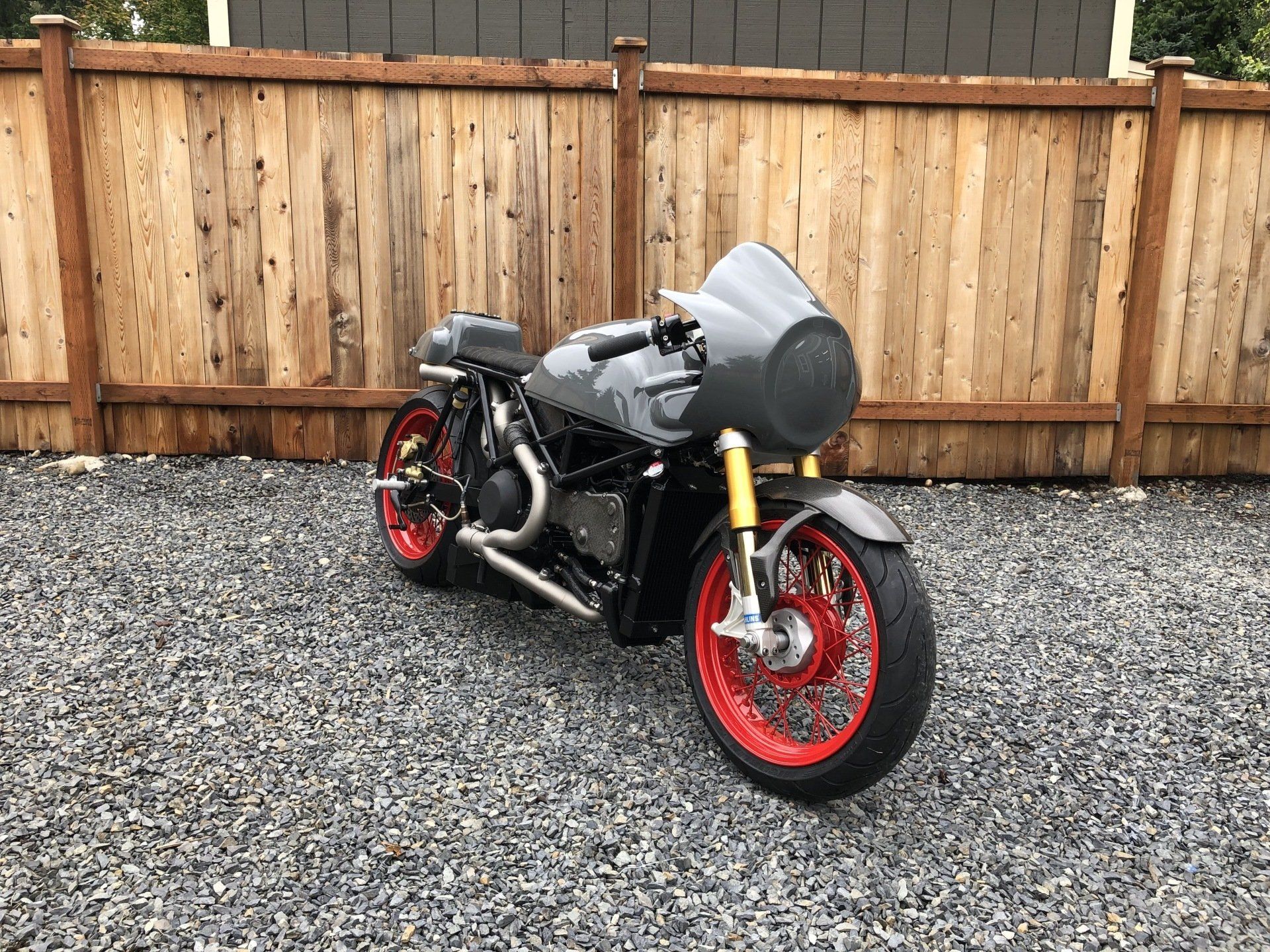 A motorcycle is parked in front of a wooden fence.