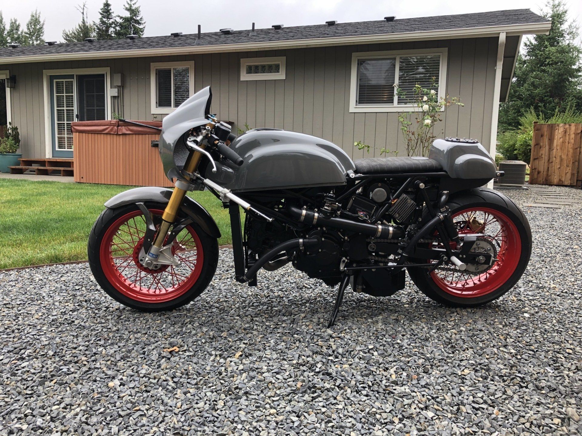 A motorcycle is parked in front of a house on gravel.