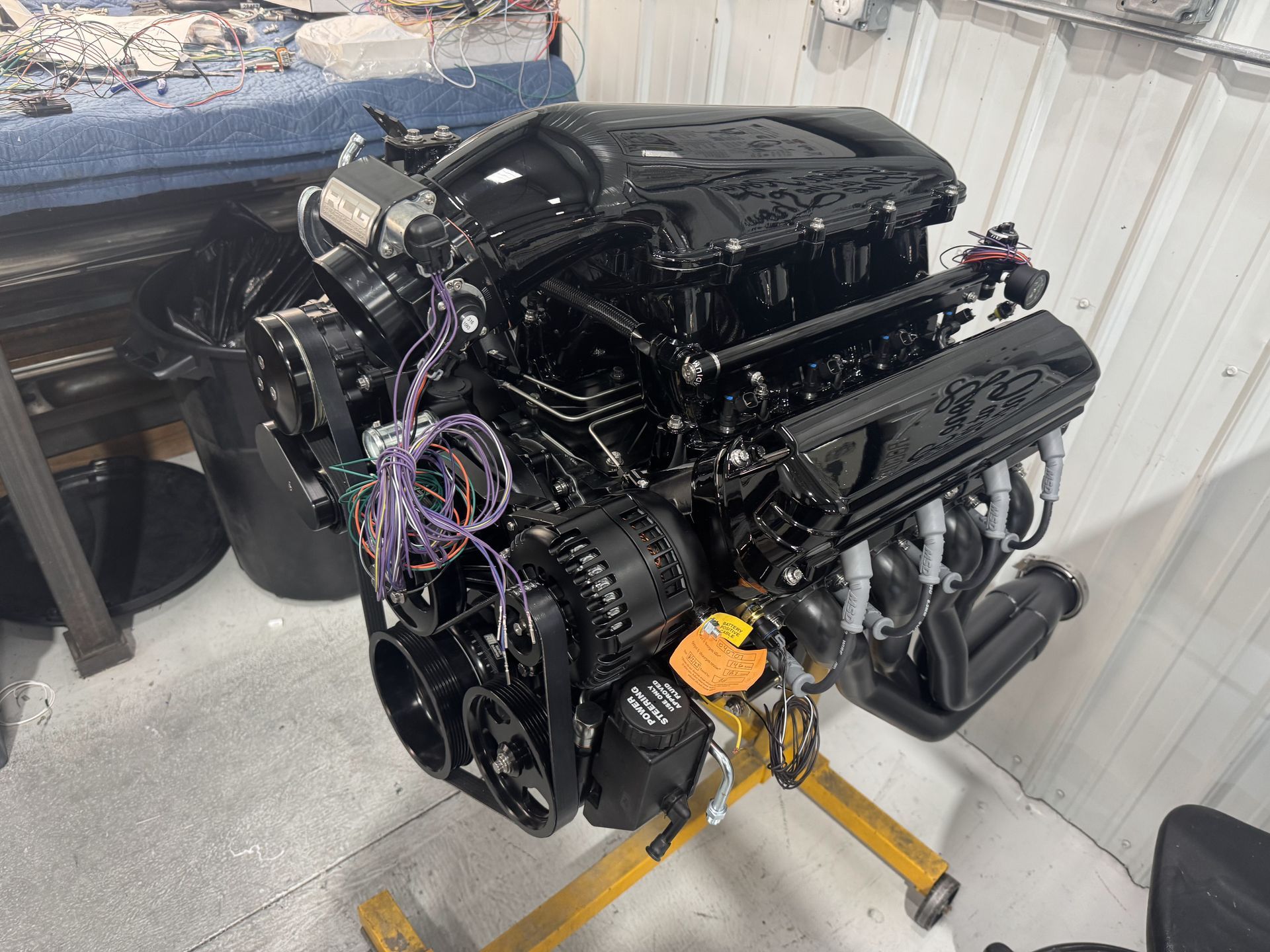 A black engine is sitting on top of a yellow stand in a garage.