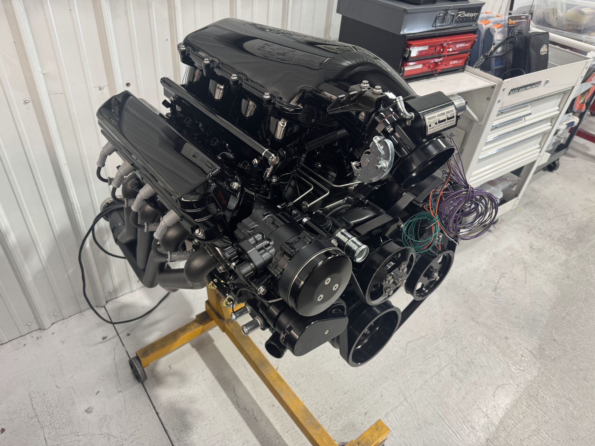 A black engine is sitting on a yellow stand in a garage.