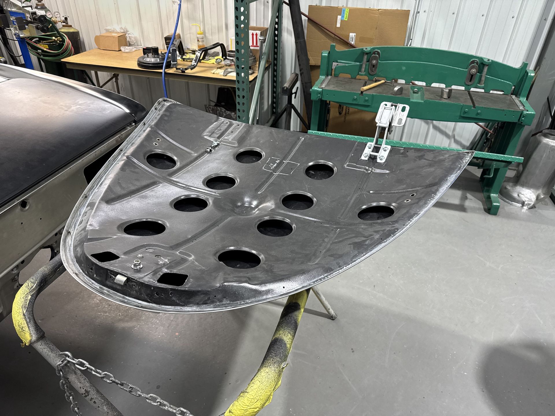 A piece of metal with holes in it is sitting on a table in a garage.